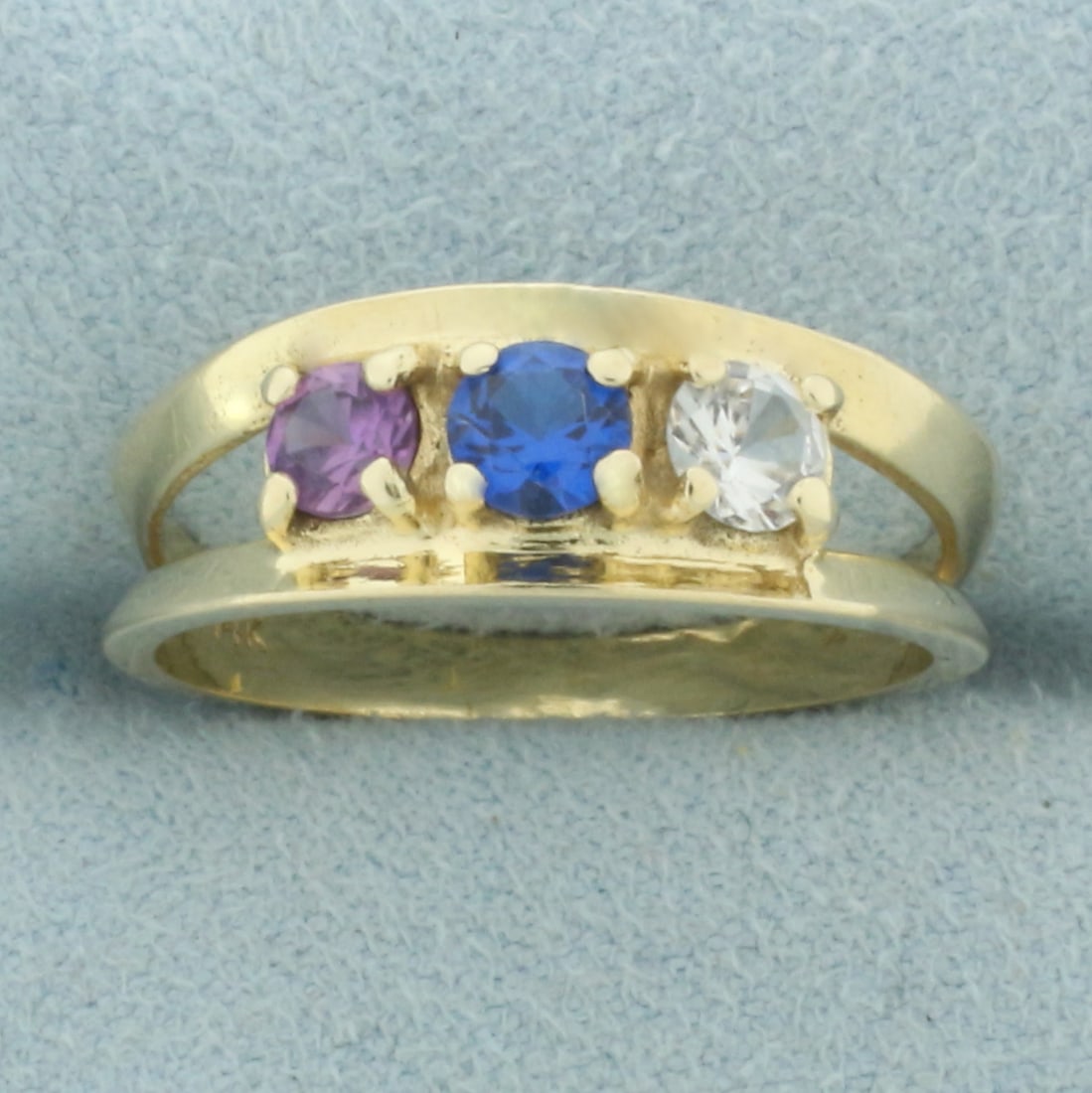 Three Stone Lab Sapphire Ring in 14k Yellow Gold: In 14k yellow gold. Contains one high quality blue, pink, and clear 4mm lab sapphire gemstones. All with excellent clarity. Size: 7.75. 2.8g.