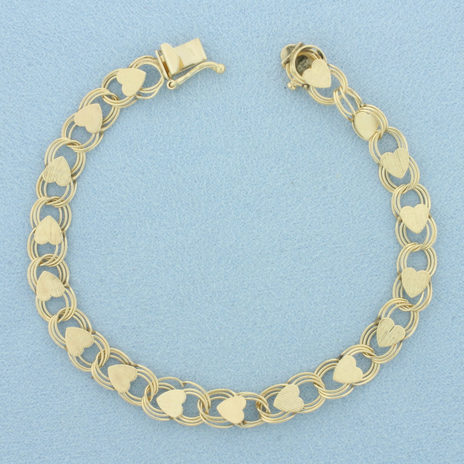 Heart Link Charm Bracelet in 14k Yellow Gold: In 14k Yellow Gold. 7 inches long. 7mm wide. Concealed slide clasp with safety latch. 6.1g.