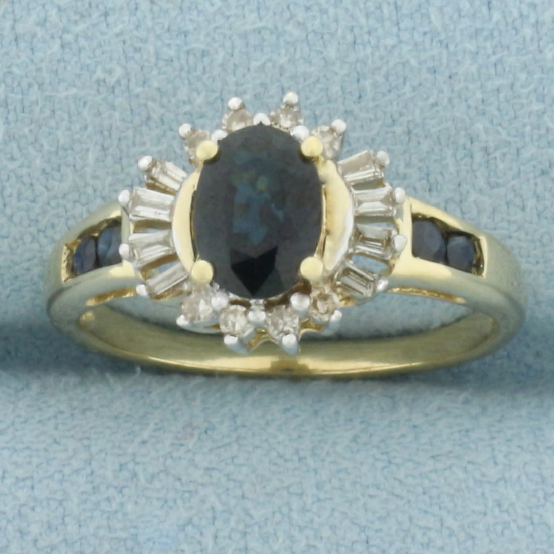 Sapphire and Diamond Halo Ring in 10k Yellow Gold: In 10k Yellow Gold. Contains one 7x5mm oval and four 2mm round high quality natural Sapphire gemstones, approximately 1.2ct TW, with deep color and excellent clarity. Also contains eight round and eig