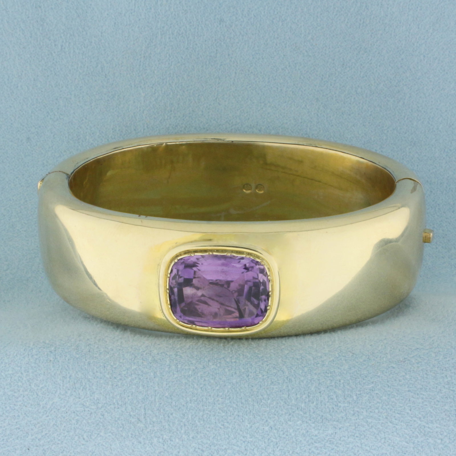 Vintage Amethyst Wide Hinged Bangle Bracelet in 14k Yellow Gold: In 14k Yellow Gold . Contains one natural high quality 16mmx13mm Amethyst gemstone with intense color and excellent clarity. 20mm wide. Interior dimensions: 2 1/4 inch by 1 3/4 inch. Minor indentation