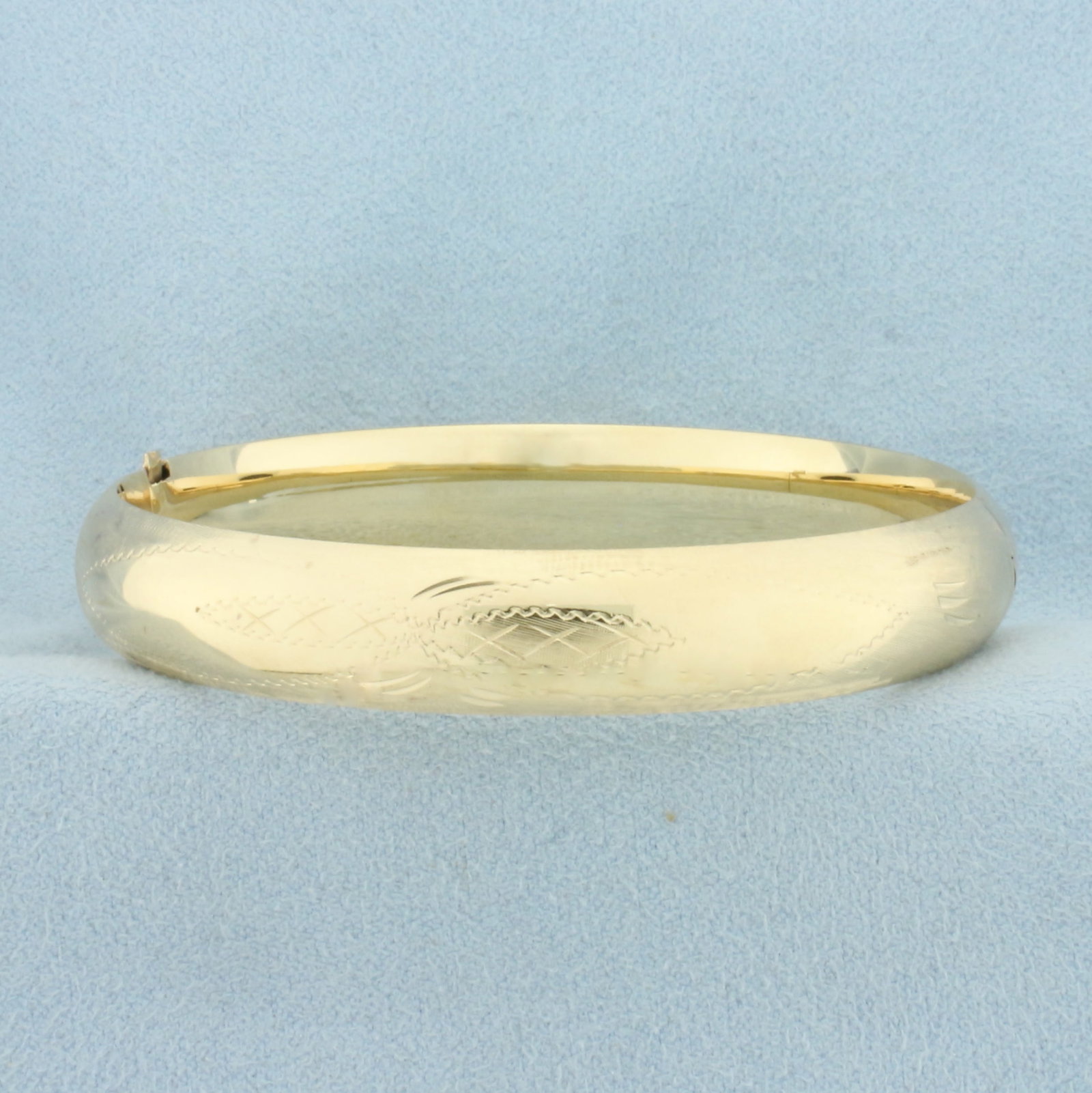 Etched Hinged Bangle Bracelet in 14k Yellow Gold: In 14k Yellow Gold. Interior dimensions: 2 3/8 by 2 1/4 inches. 10mm wide. Hinged slide locking clasp. 14.0g.