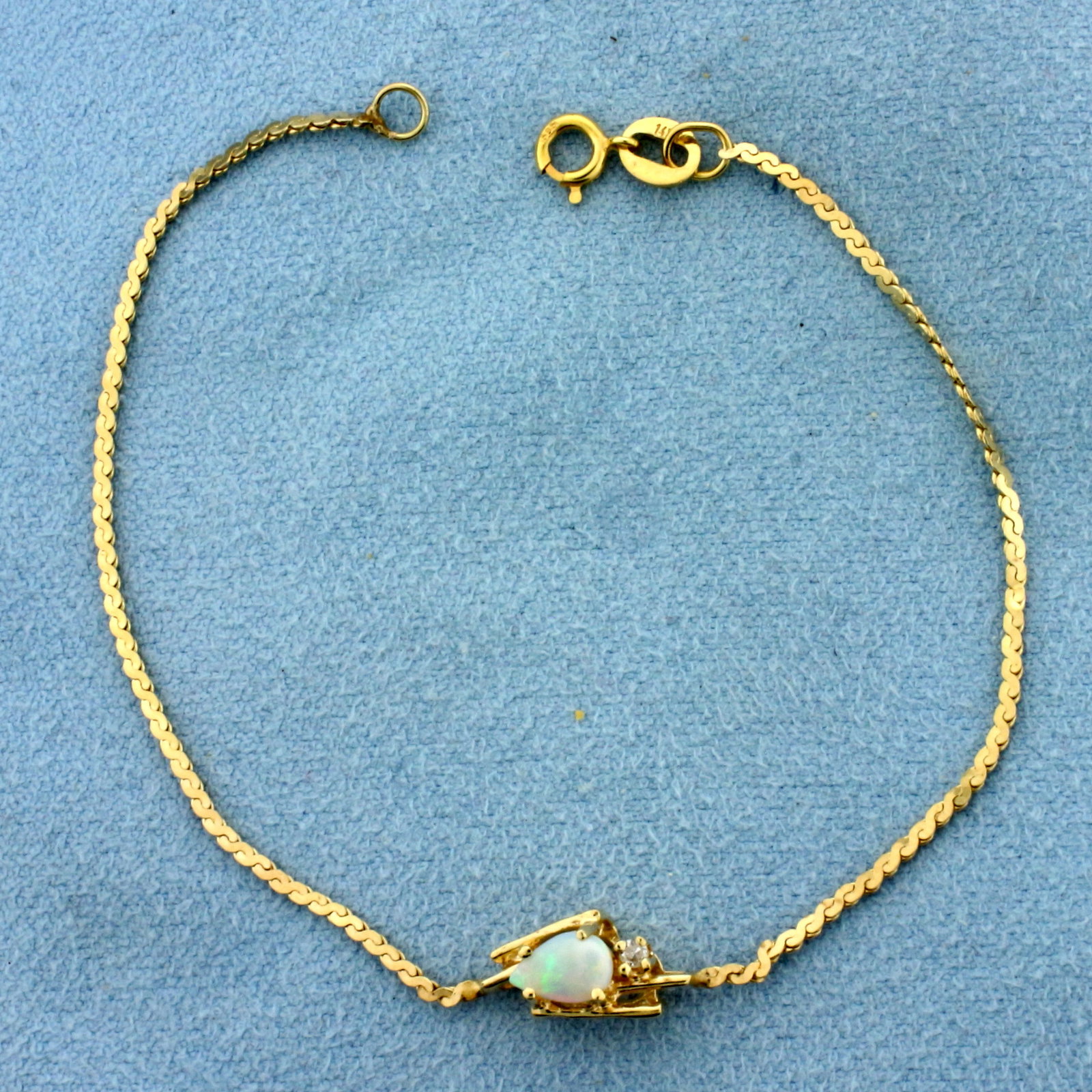 Opal and Diamond Bracelet in 14k Yellow Gold: In 14k Yellow Gold. Contains one 6mm high quality natural Opal gemstone with intense play of color, flashes of green, blue, orange, and red. Also contains one .02ct high quality diamond. 6 1/2 inches