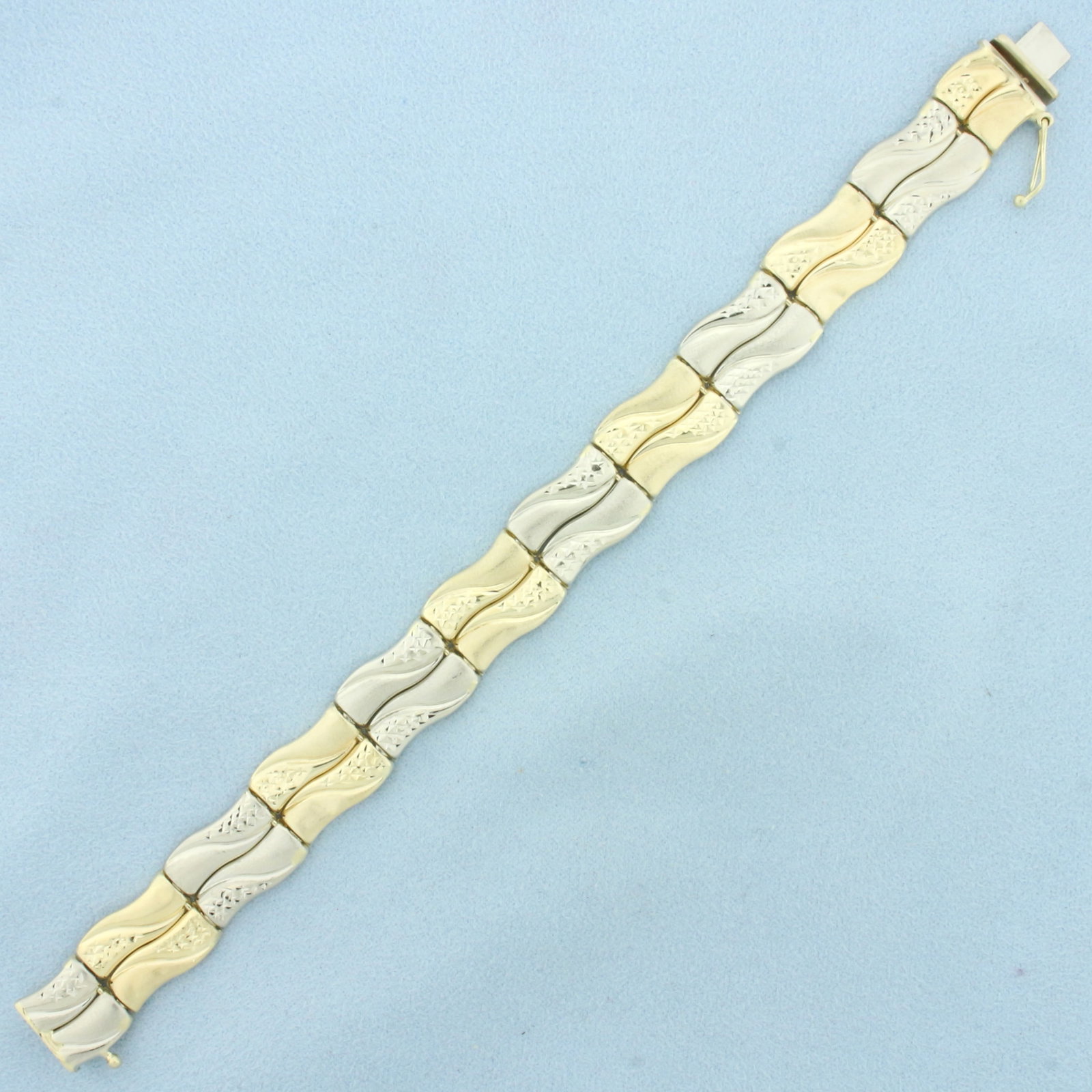 Diamond Cut Wave Design Bar Bracelet in 14k Yellow and White Gold: In 14k yellow and white gold. 7 1/8 inches long and 1/2 inches wide. Satin and diamond cut details. Minor indentation, not noticeable. Concealed slide clasp with safety latch. 15.3g.