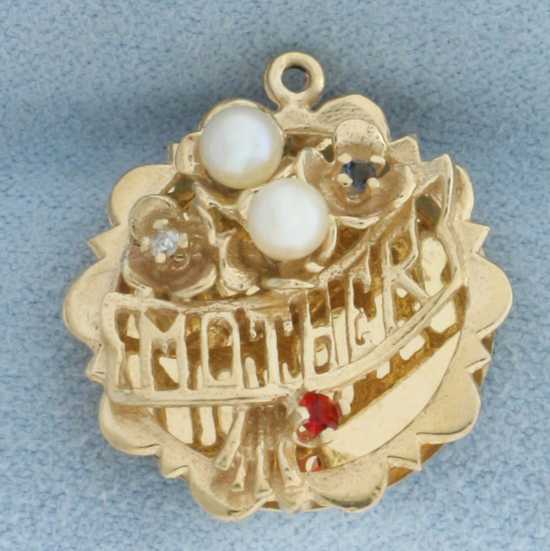Mother Pearl, Ruby, Sapphire, and Diamond Charm in 14k Yellow Gold: In 14k Yellow Gold. Contains one 2mm Ruby and Sapphire gemstones and one 1/2pt diamond. 7/8 inch long. 3/4 inch wide. Can engrave name on back. 3.9g.