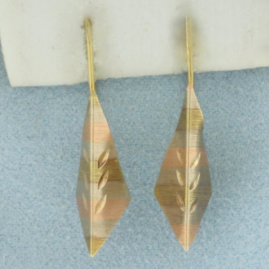 Tri-Color Kite Design Earrings in 14k Yellow, Rose, and White Gold: In 14k Yellow, Rose, and White Gold. 1 inch long. 1/4 inch wide. Kidney ear backs. 0.9g.
