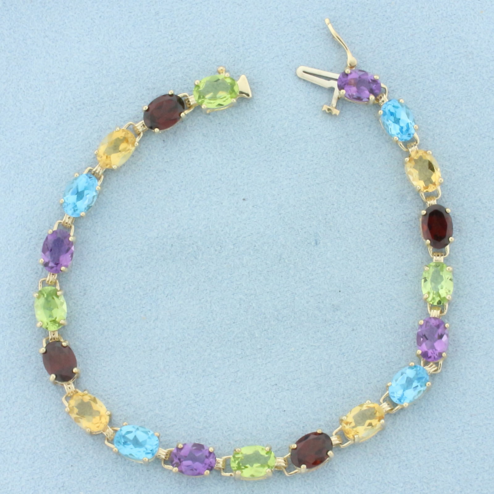 Rainbow Gemstone Tennis Bracelet in 10K Yellow Gold: In 10k yellow gold. Measures 7.25 inches long. Contains high quality natural 7mm gemstones: 4-peridot, 4-garnet, 4-citrine, 4-blue topaz, and 4-amethyst. Approximately 24ct TW. All gems have bright co