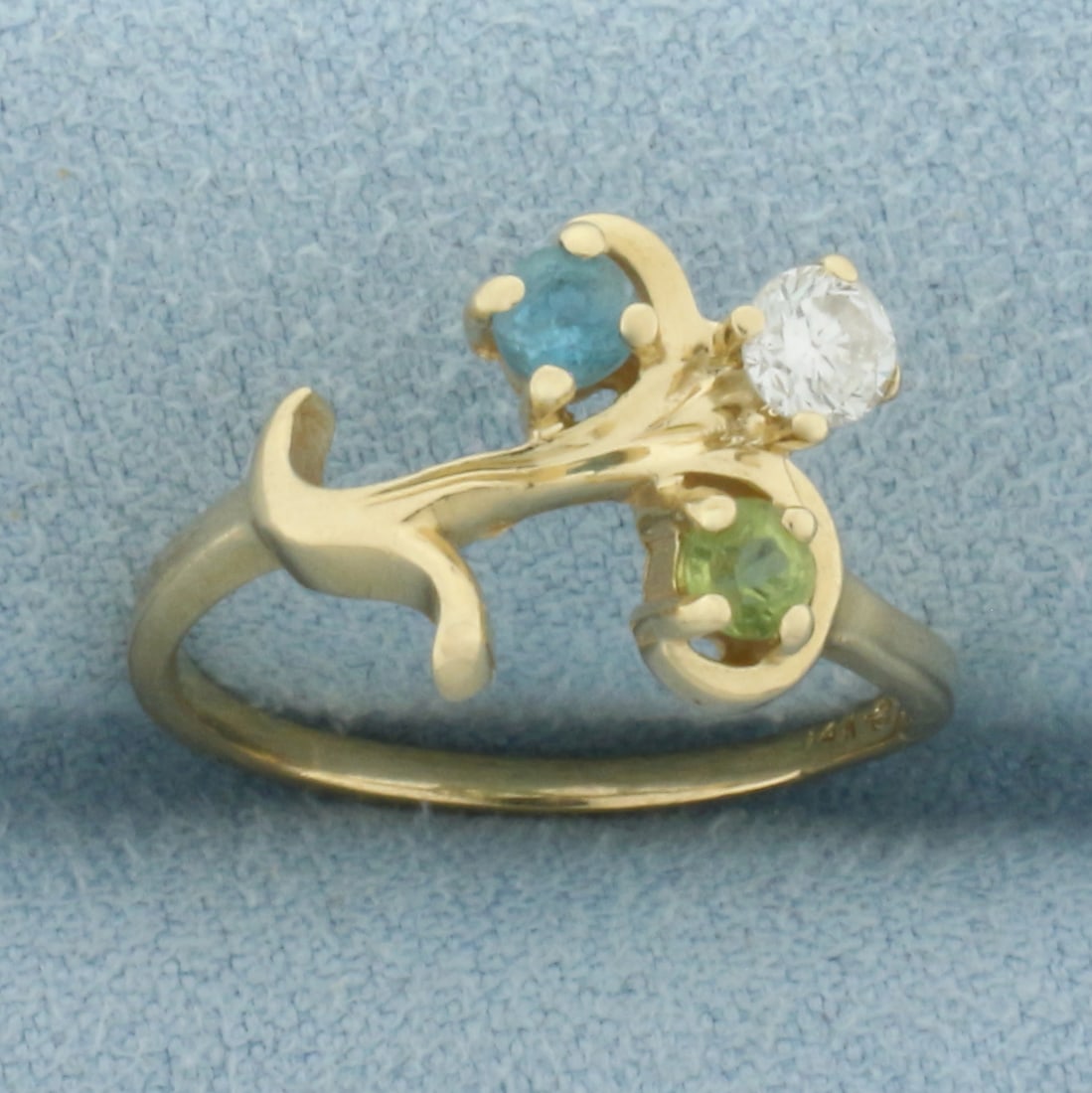 Gemstone Branch Design Ring in 14k Yellow Gold: In 14k Yellow Gold. Contains one Blue Topaz and one Peridot 3mm gemstones with bright color and excellent clarity. Also contains one .1ct high quality diamond VS clarity/H color. 11mm wide spread at t