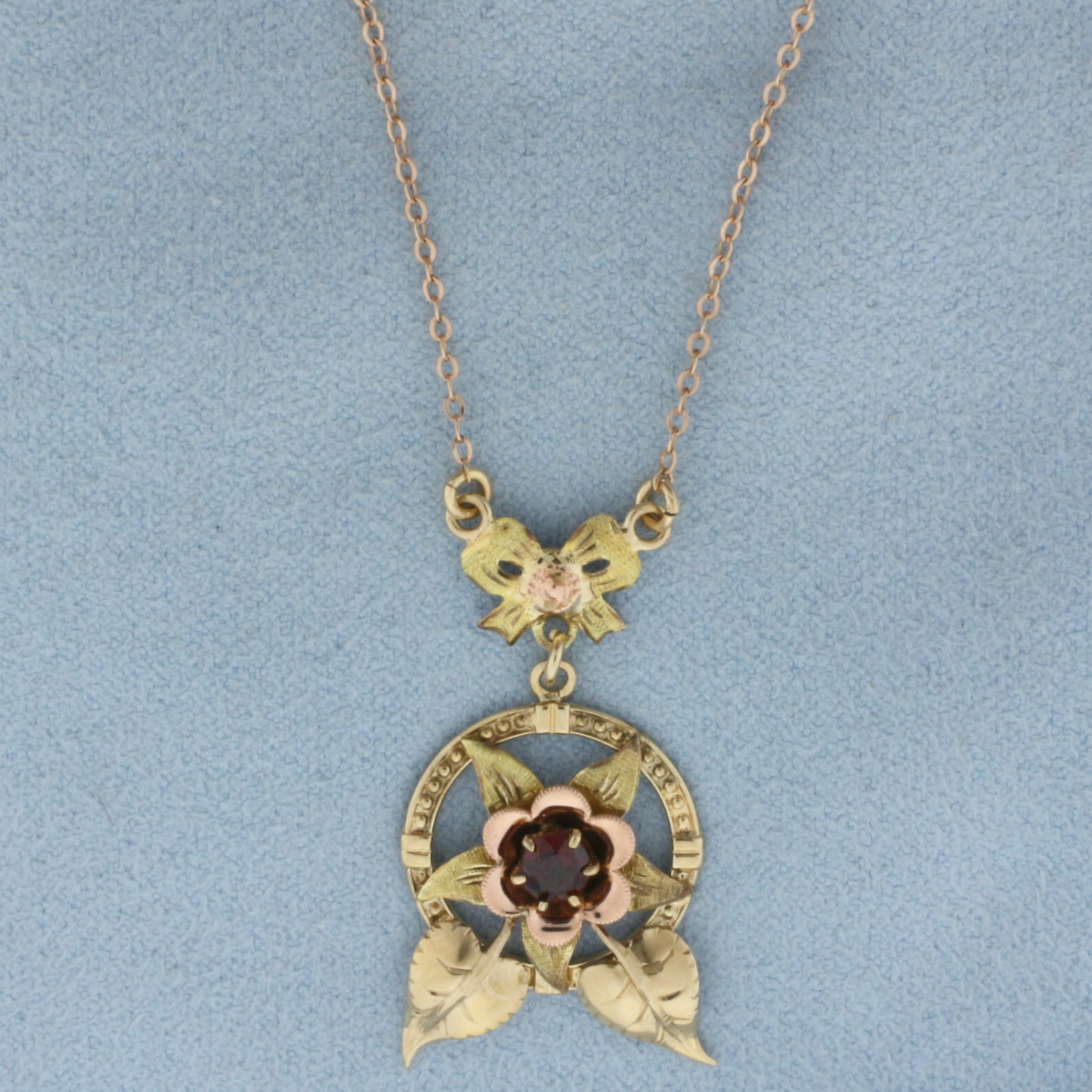 Vintage Lavalier Garnet Flower Necklace In 14k and 10k Yellow Gold: Chain in 14k gold, pendant in 10k gold. Contains one 1/4ct high quality natural Garnet gemstone with intense color and excellent clarity. 18 inches long. 1 1/4 by 3/4 inch wide center design. Spring c