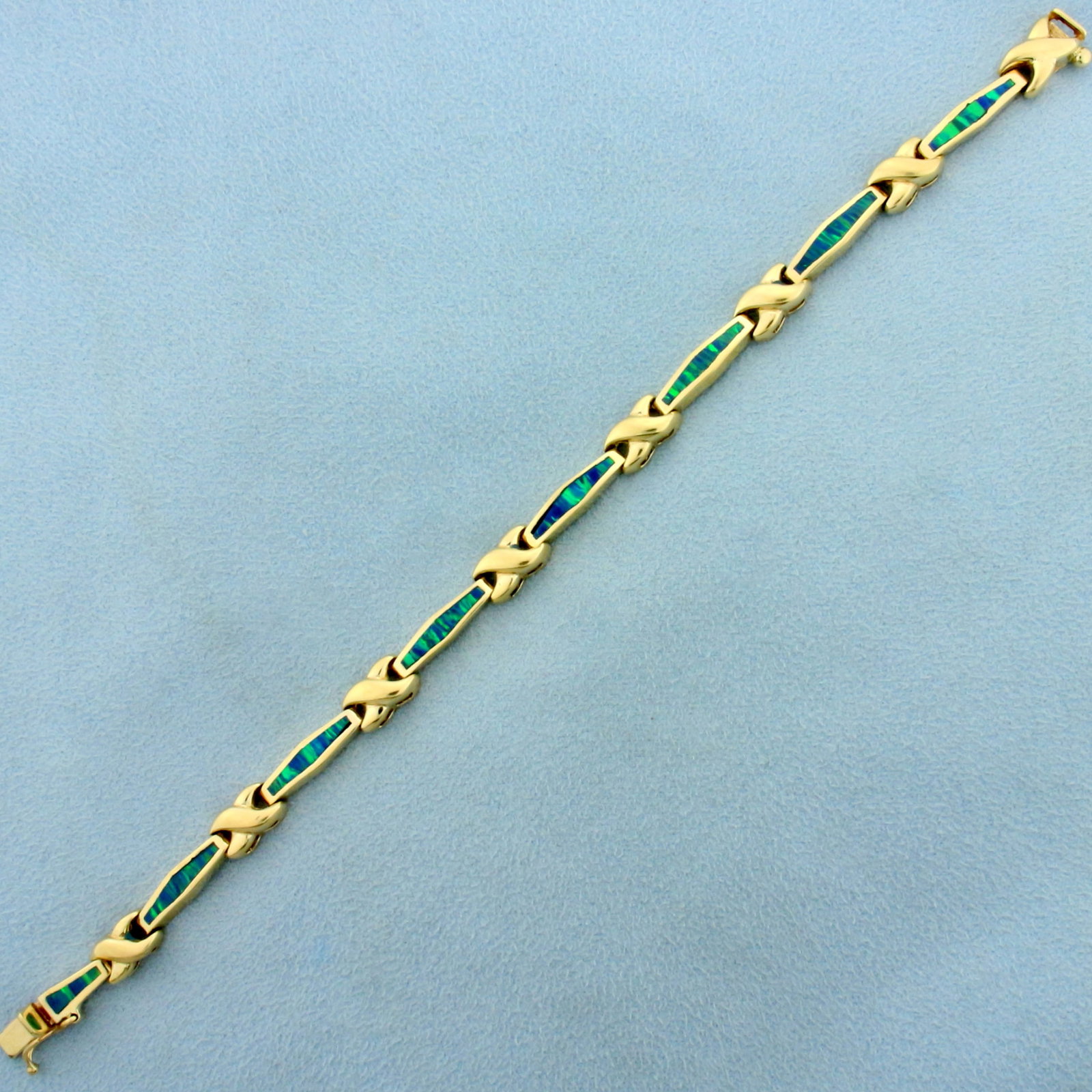 Black Opal Line Tennis Bracelet in 14K Yellow Gold: In 14K Yellow Gold. Contains seven high quality 13x2mm and one 8x2mm Black Opal gemstones with intense play of color with flashes of green and blue. One opal stone has very small crack in it, not noti