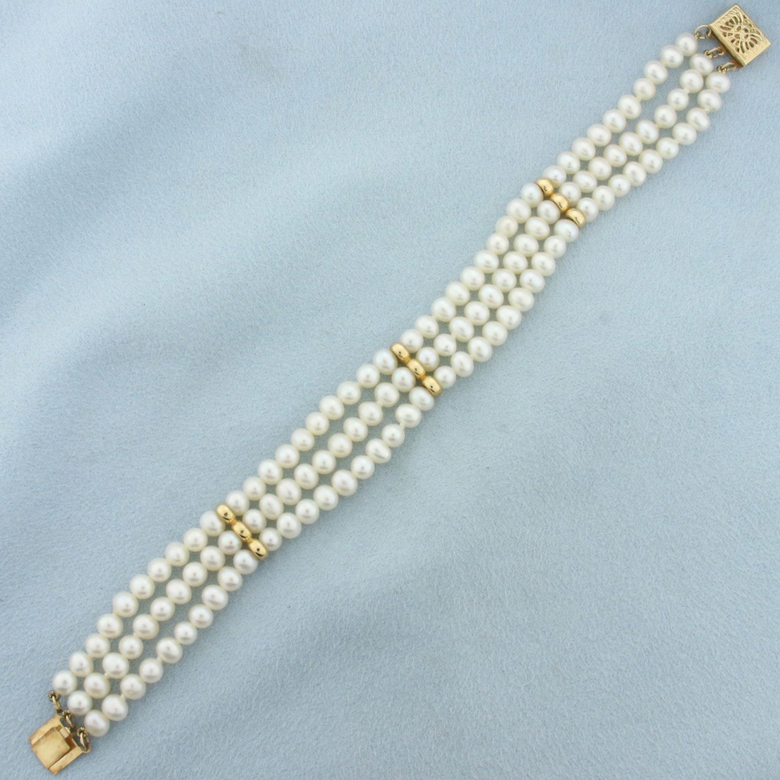 Triple Strand Cultured Pearl Bracelet in 14k Yellow Gold: 14k yellow gold clasp and spacers. Hand knotted. High quality cultured pearls range from 4.5-4.8mm each with high luster. Decorative Filigree clasp. 14.8g.