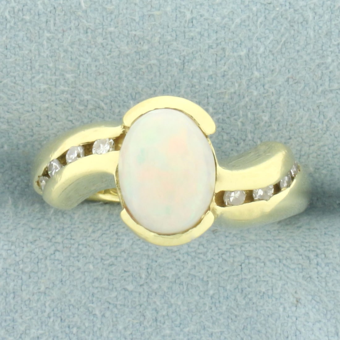 Opal and Diamond Ring in 18k Yellow Gold: In 18k yellow gold. Contains one high quality 9mm by 7mm high quality natural Opal gemstone with intense play of color and flashes of yellow, green, purple, and orange. Also contains eight high qualit
