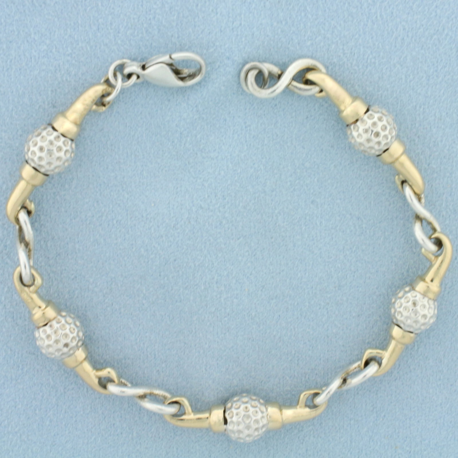 Golf Ball Link Bracelet in 14K Yellow Gold and Sterling Silver: In 14K Yellow Gold and Sterling Silver. 7 1/2 inches long, 7.9mm wide. Lobster clasp. 26.6g.