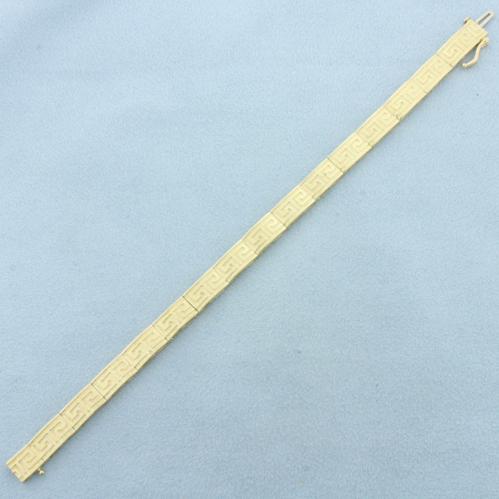 Greek Key Bracelet in 14k Yellow Gold: In 14k Yellow Gold. 7 inches long. 1/4 inch wide. Concealed slide clasp with safety latch. 15.4g.
