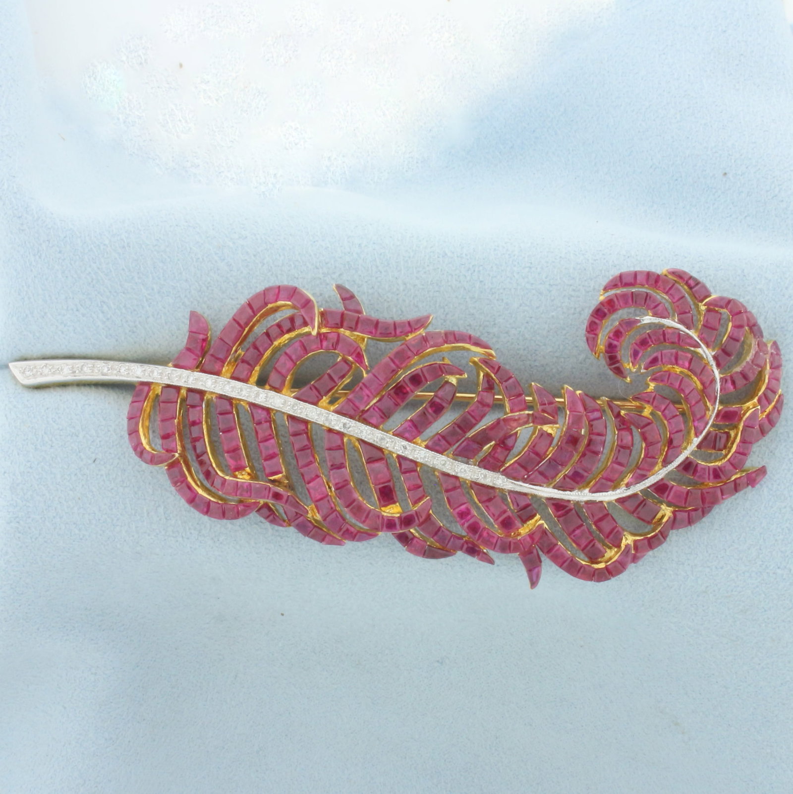 Ruby and Diamond Feather Brooch in 18k Yellow Gold: In 18k yellow gold. Contains 306 ruby gemstones, approximately 15cts TW, with vibrant color and excellent clarity. Accented by 27 diamonds, 1/4ct TW, VS clarity/G color. 3.5 inches long x 1.5