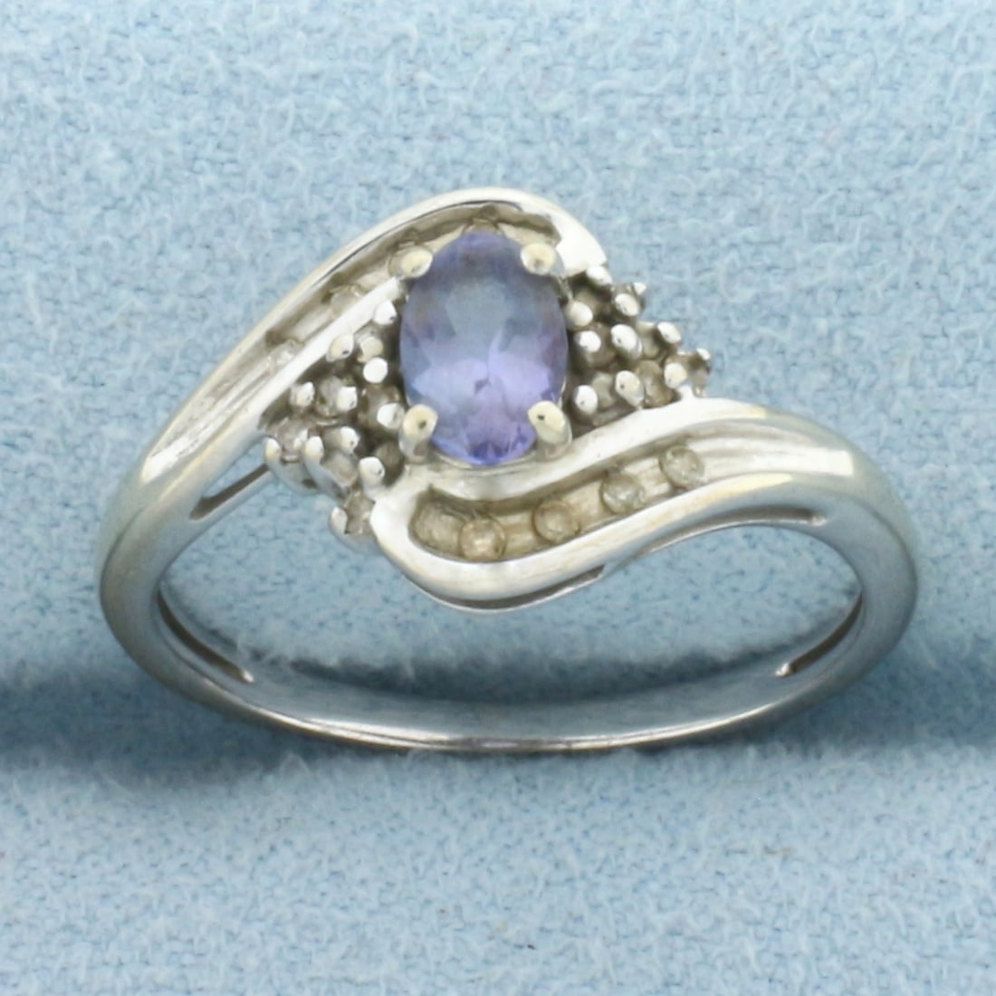 Tanzanite and Diamond Ring in 10k White Gold: In 10k White Gold. Contains one high quality 6mm Natural Tanzanite gemstone with bright color and excellent clarity. Also contains eighteen high quality 1/2pt diamonds. 10.5mm wide at center. Size 7.