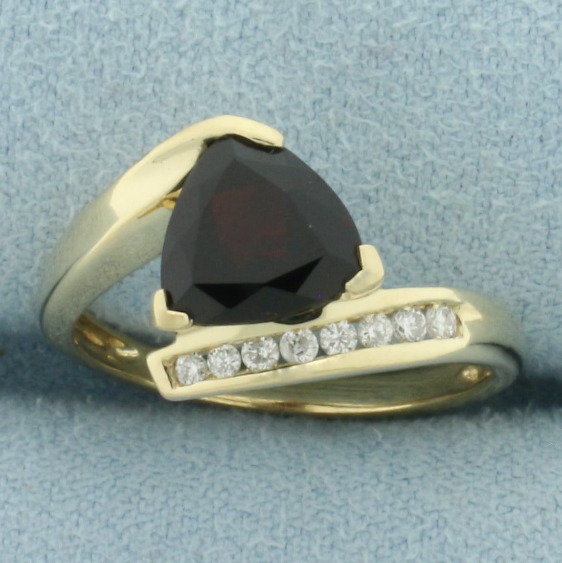 Garnet and Diamond Bypass Ring in 10k Yellow Gold: In 10k Yellow Gold. Contains one 8mm high quality trillion natural Garnet gemstone with intense color and excellent clarity. Also contains eight high quality .01ct diamonds. 11.2mm wide at center of r