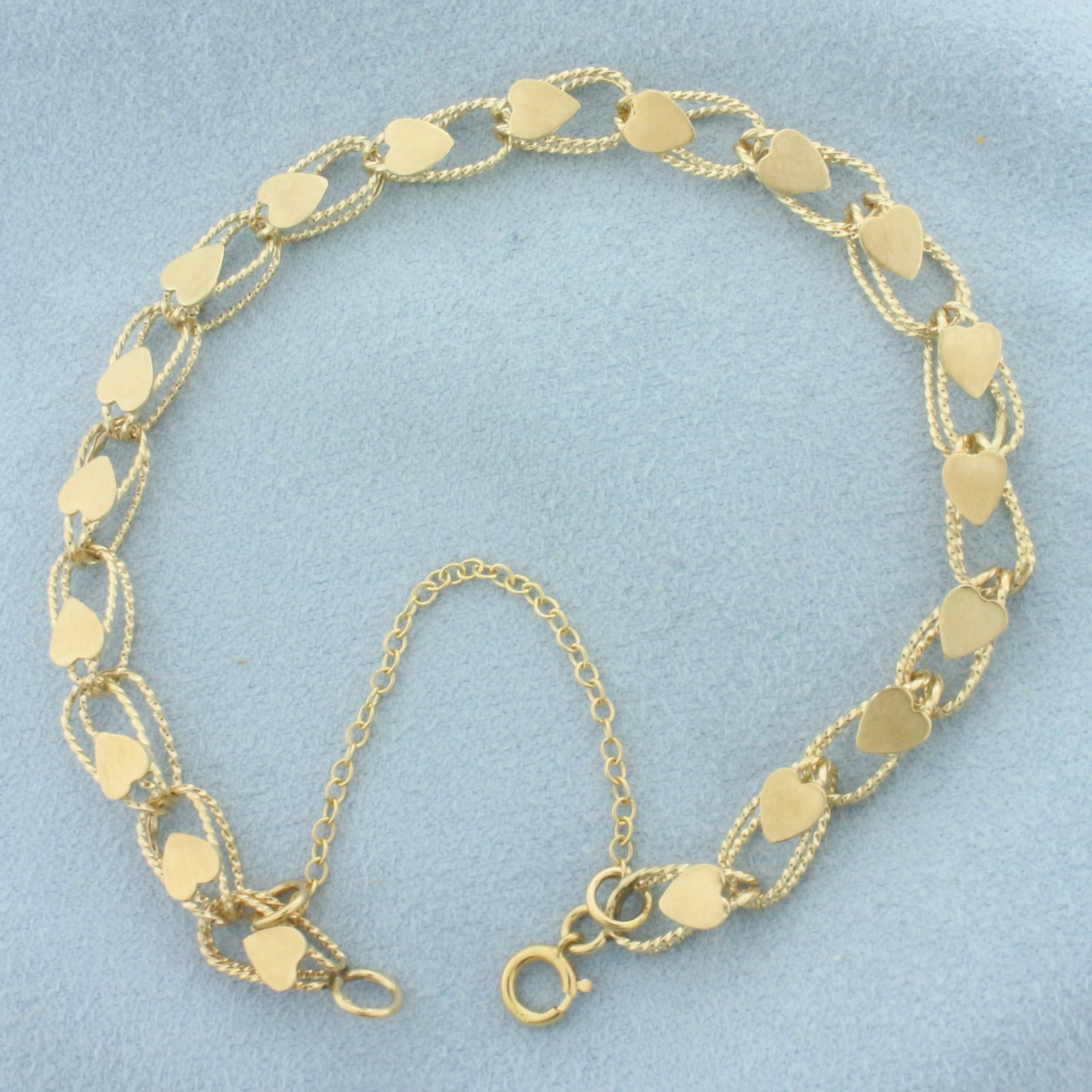 Heart Link Bracelet in 14k Yellow Gold: In 14k Yellow Gold. 7 1/2 inches long. 6mm wide. Can attach charms or wear as it is. Spring clasp with safety chain. 6.0g.