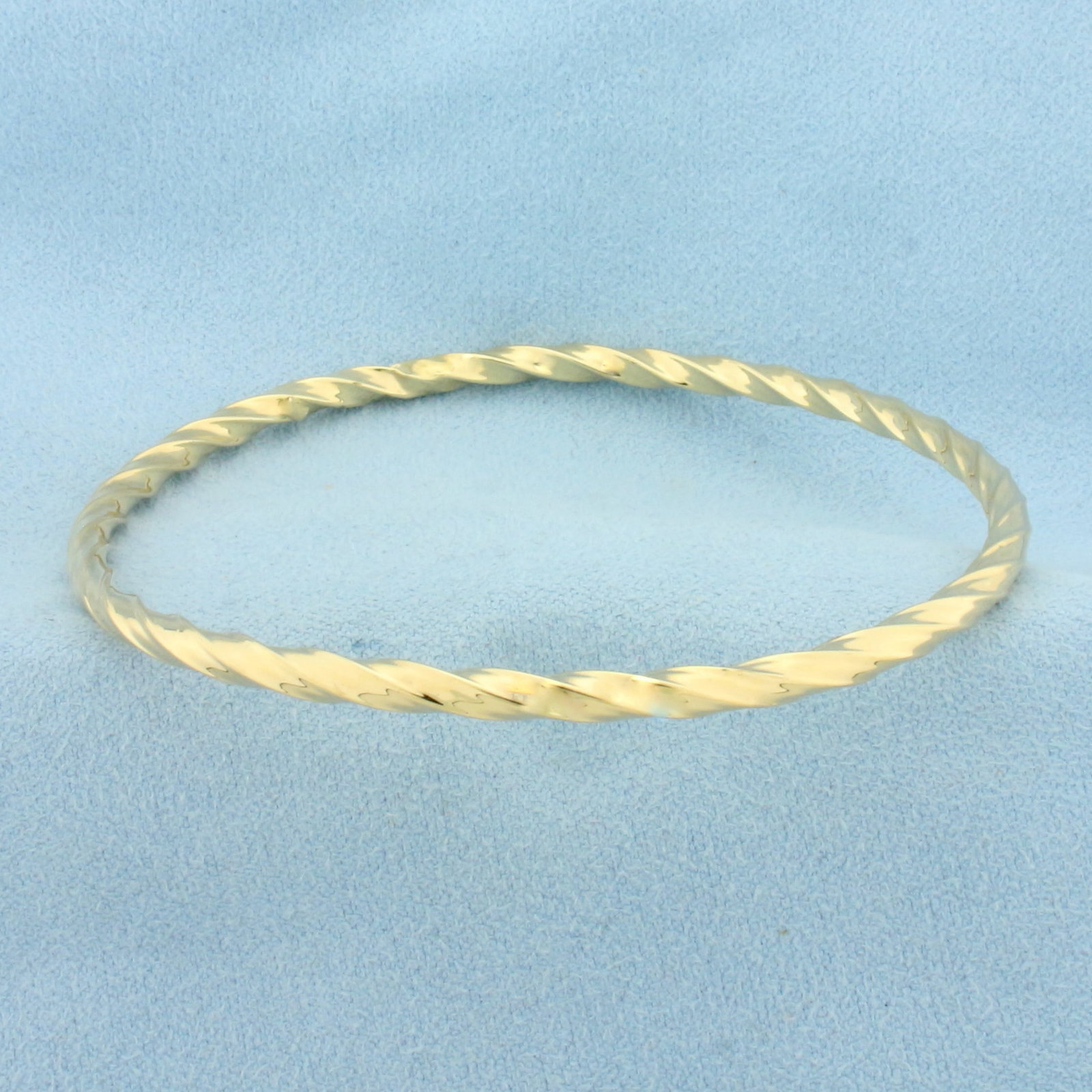 Twisting Design Bangle Bracelet in 10k Yellow Gold: In 10k Yellow Gold. 2 5/8 inch interior diameter. 3.4mm wide. One small dent, very difficult to see when worn. 2.9g.