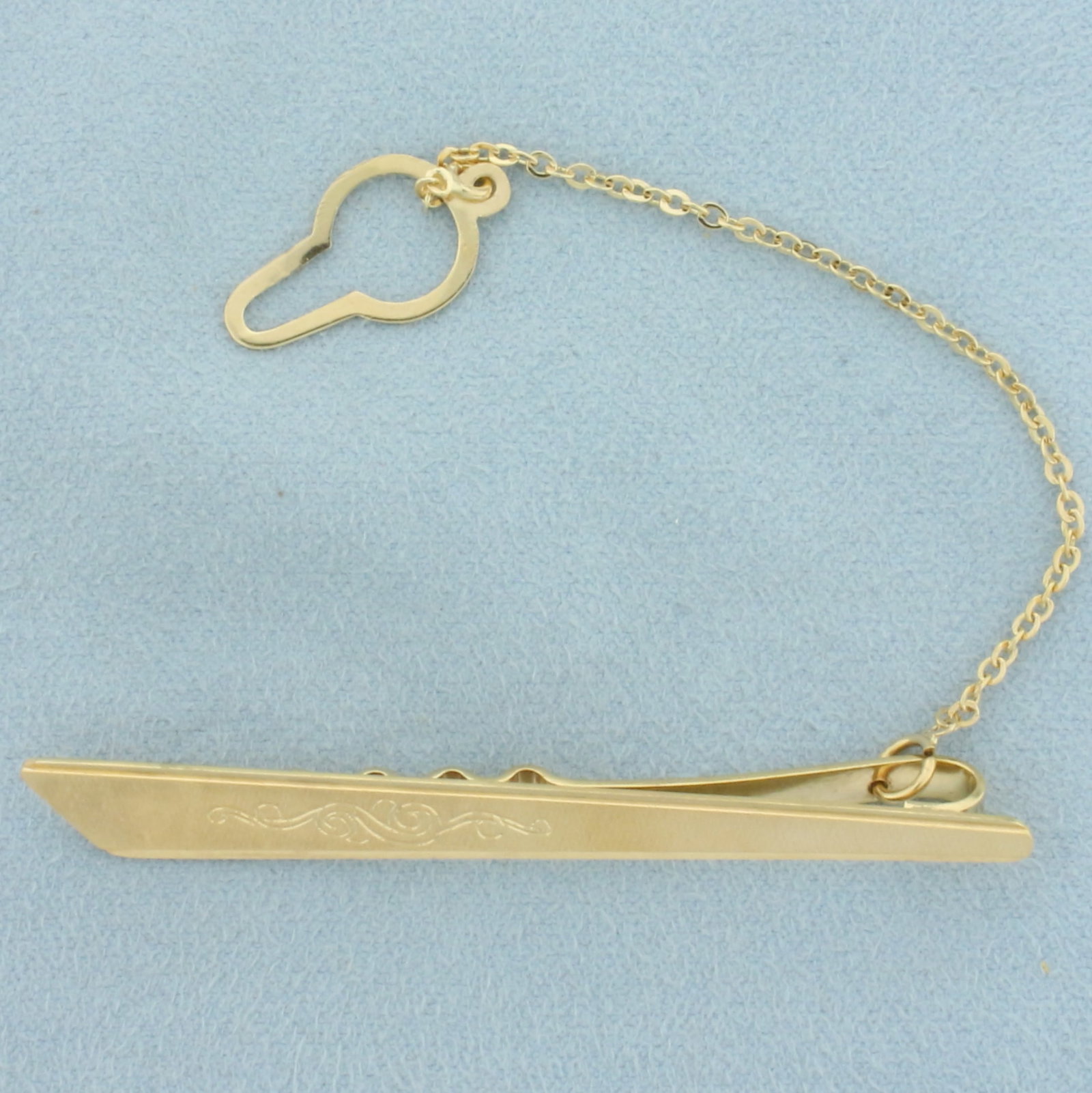 Vintage Engraved Tie Bar Clip with Chain in 18k Yellow Gold: In 18k yellow gold. 2 1/2 inches long x 5/16 inches wide (main clip piece). Unusual brushed finish for unique reflection of light and scroll engraved design. 6.7g.