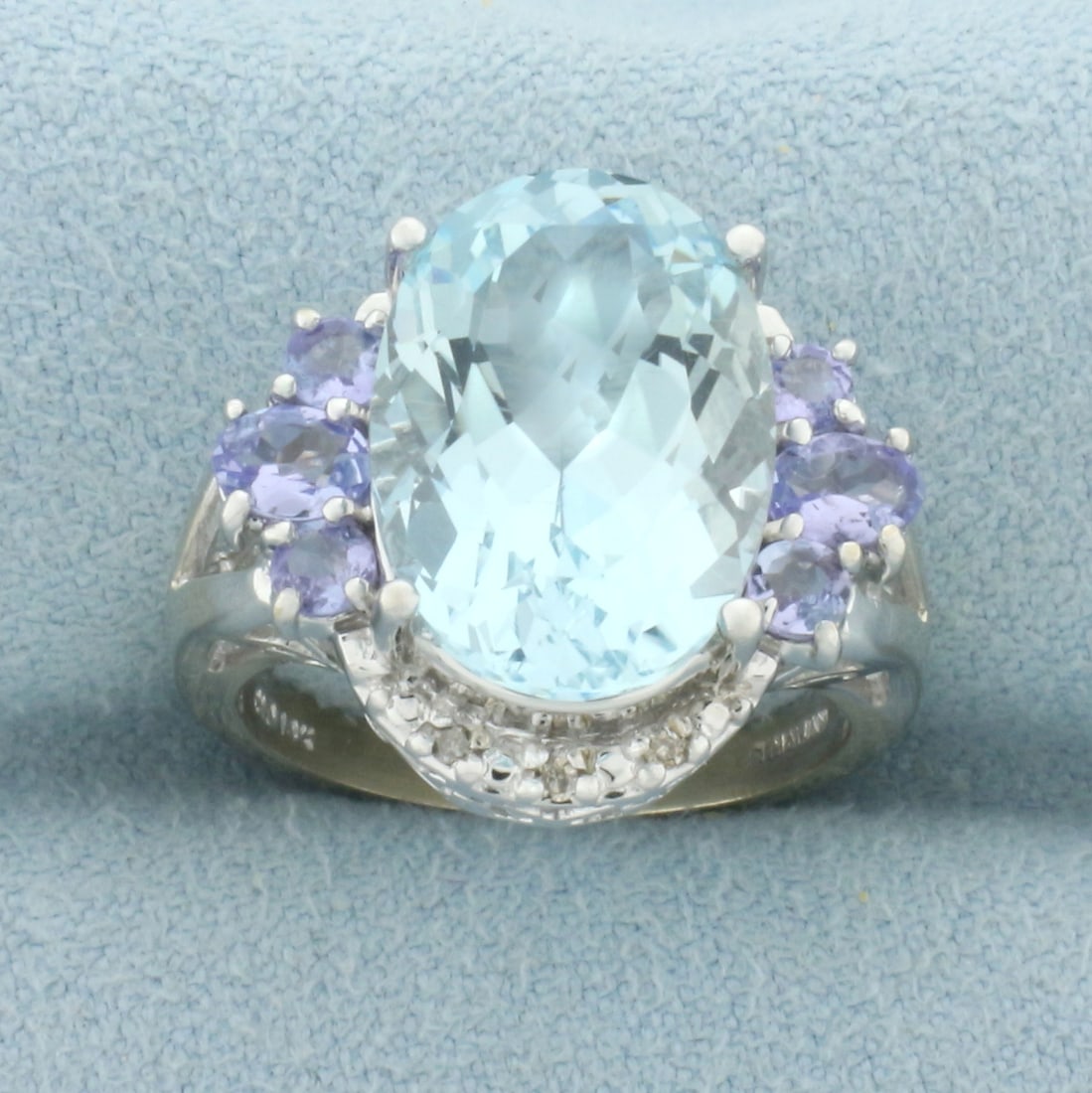 Aquamarine, Tanzanite, and Diamond Ring in 14k White Gold: In 14k white gold. Contains one high quality natural 14mm by 10mm 5ct Aquamarine gemstone with bright color and excellent clarity. Also contains six high quality tanzanite gemstones, 2/3ct TW, with