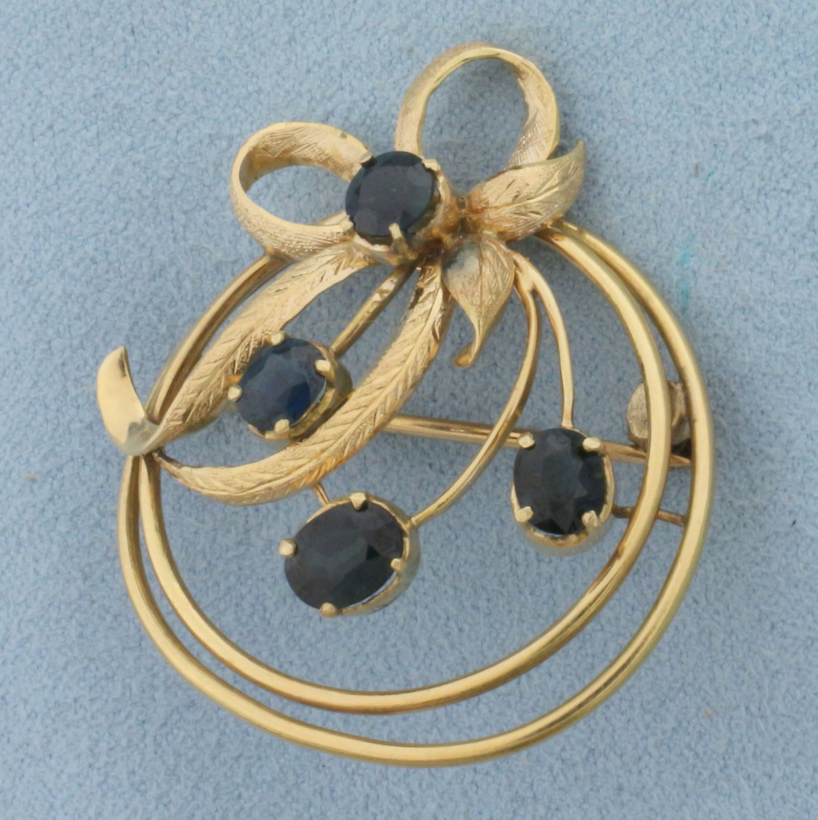 Vintage Sapphire Bow Design Brooch in 14K Yellow Gold: In 14K Yellow Gold. Contains one 6mm oval, two 5mm oval, and one 5mm round high quality natural sapphire gemstones with deep blue color and excellent clarity. Over 2cts TW. 1 1/2 inches long. 7.8g.