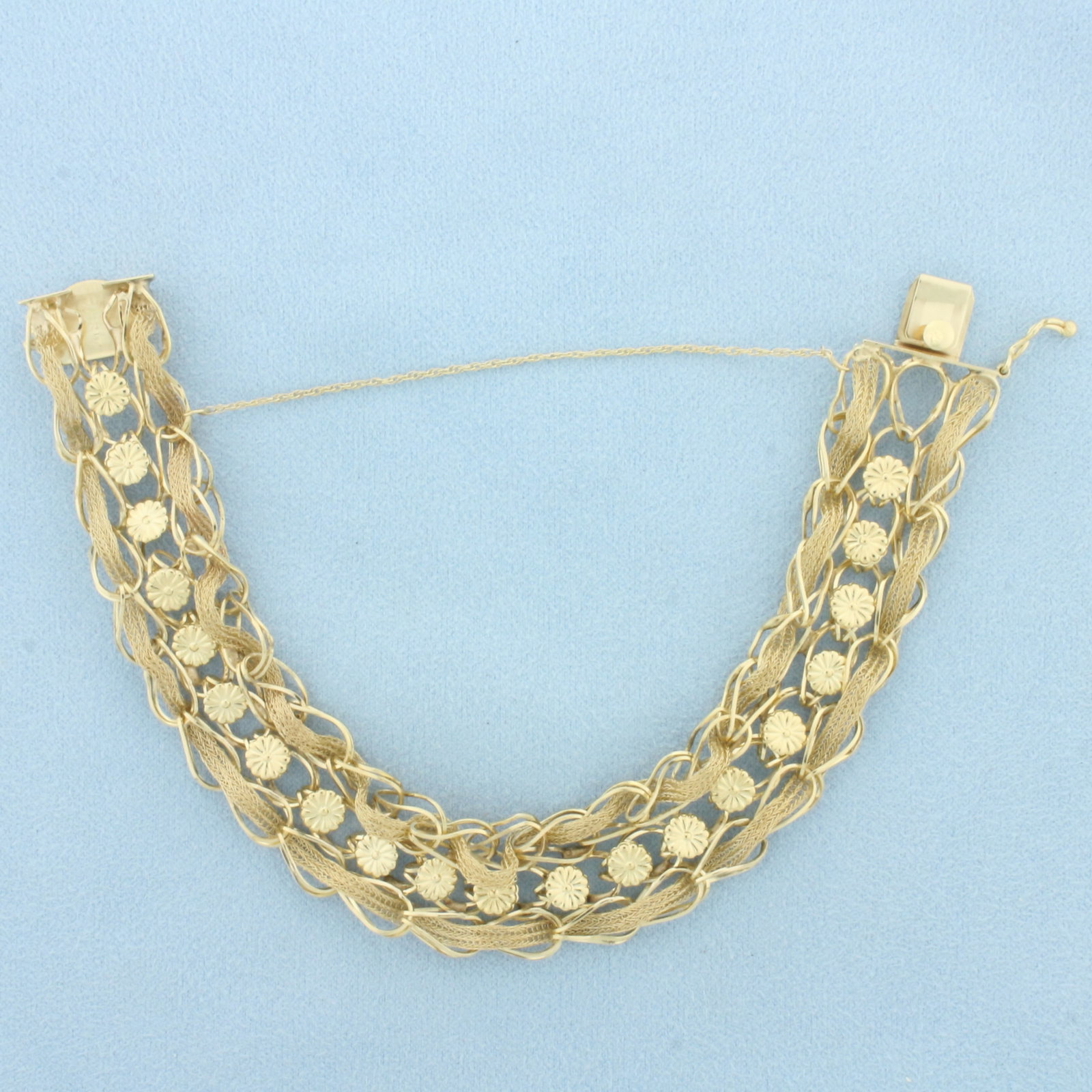 Woven Flower Design Bracelet in 14k Yellow Gold: In 14k Yellow Gold. 7 3/4 inches long. 5/8 inch wide. Concealed slide clasp with safety latch and chain. 19.5g.