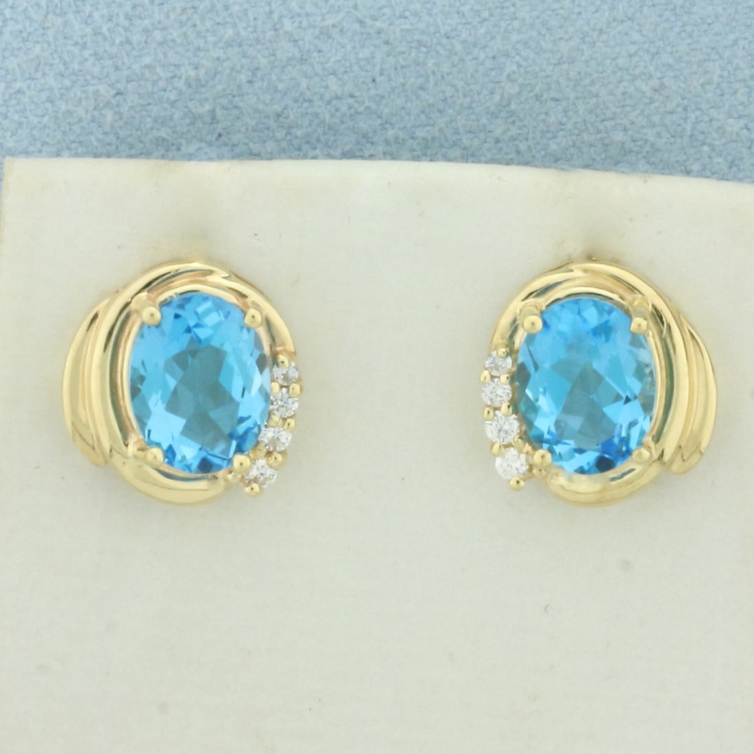 Swiss Blue Topaz and Diamond Earrings in 14k Yellow Gold: In 14k Yellow Gold. Contains two 9x7mm high quality natural Swiss Blue Topaz gemstones, approximately 5ct TW, with electric blue color and excellent clarity. Also contains eight .01ct TW high quality 