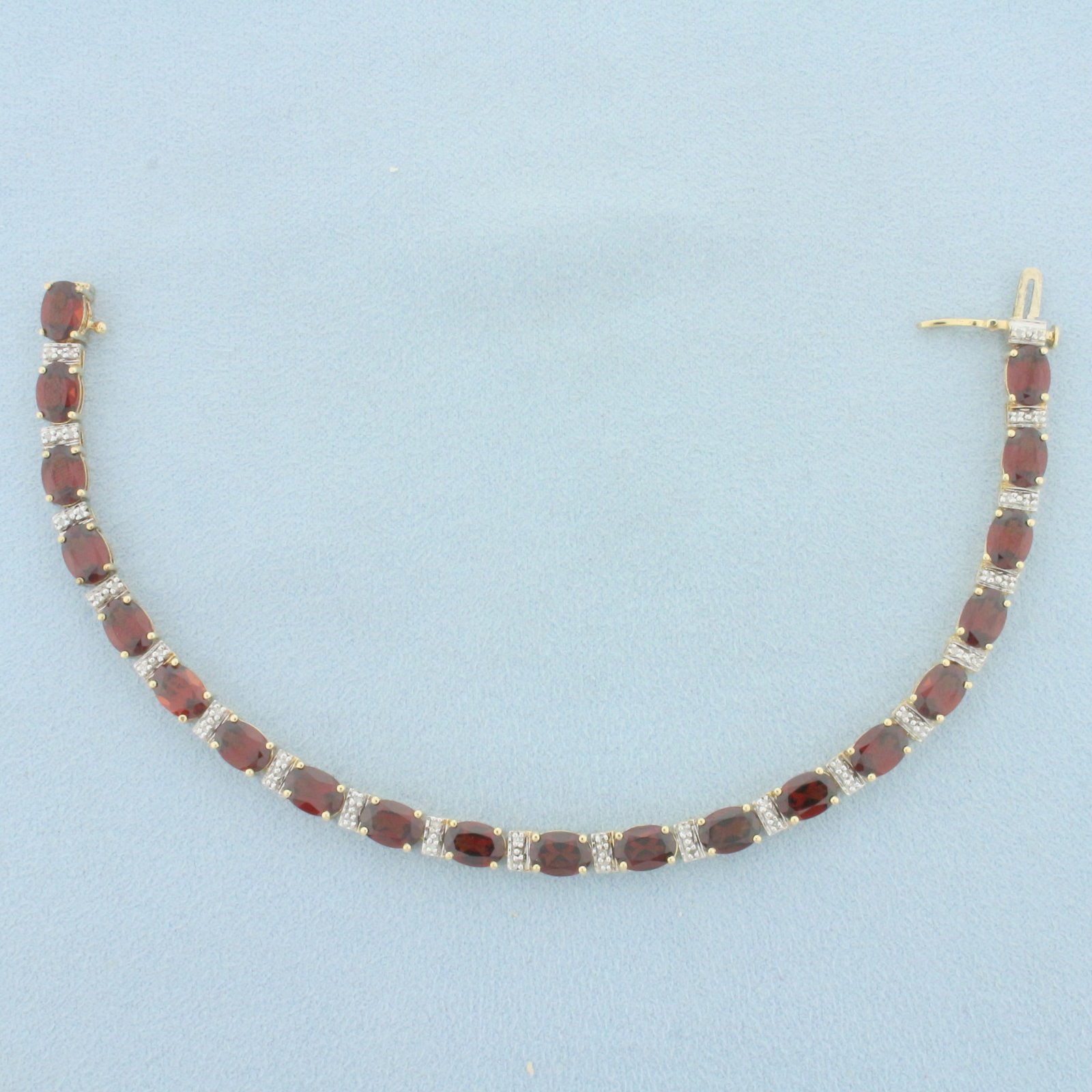 Garnet and Diamond Tennis Bracelet in 14k Yellow Gold: In 14k yellow Gold. Contains 20 high quality natural 1ct oval garnet gemstones with intense color and excellent clarity. Also contains forty 1/2pt diamonds. Concealed slide closure with safety latch. 