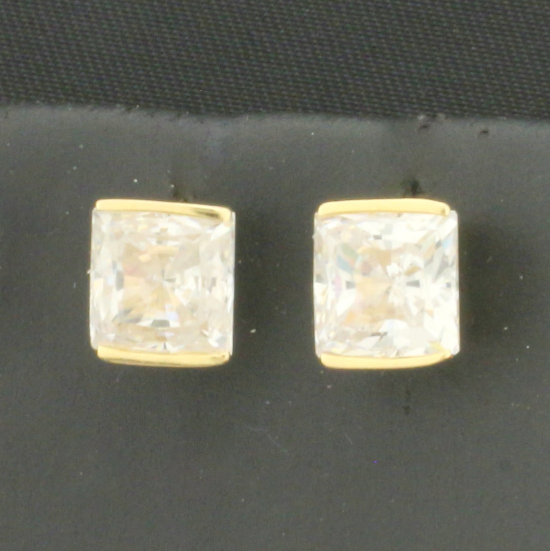 Bezel Set Princess CZ Stud Earrings in 14k Yellow Gold: In 14k Yellow Gold. Contains two 6.5mm high quality princess cut CZ gemstones, approximately 1ct each, with excellent cut and clarity for added brilliance. Friction backs. 2.3g.