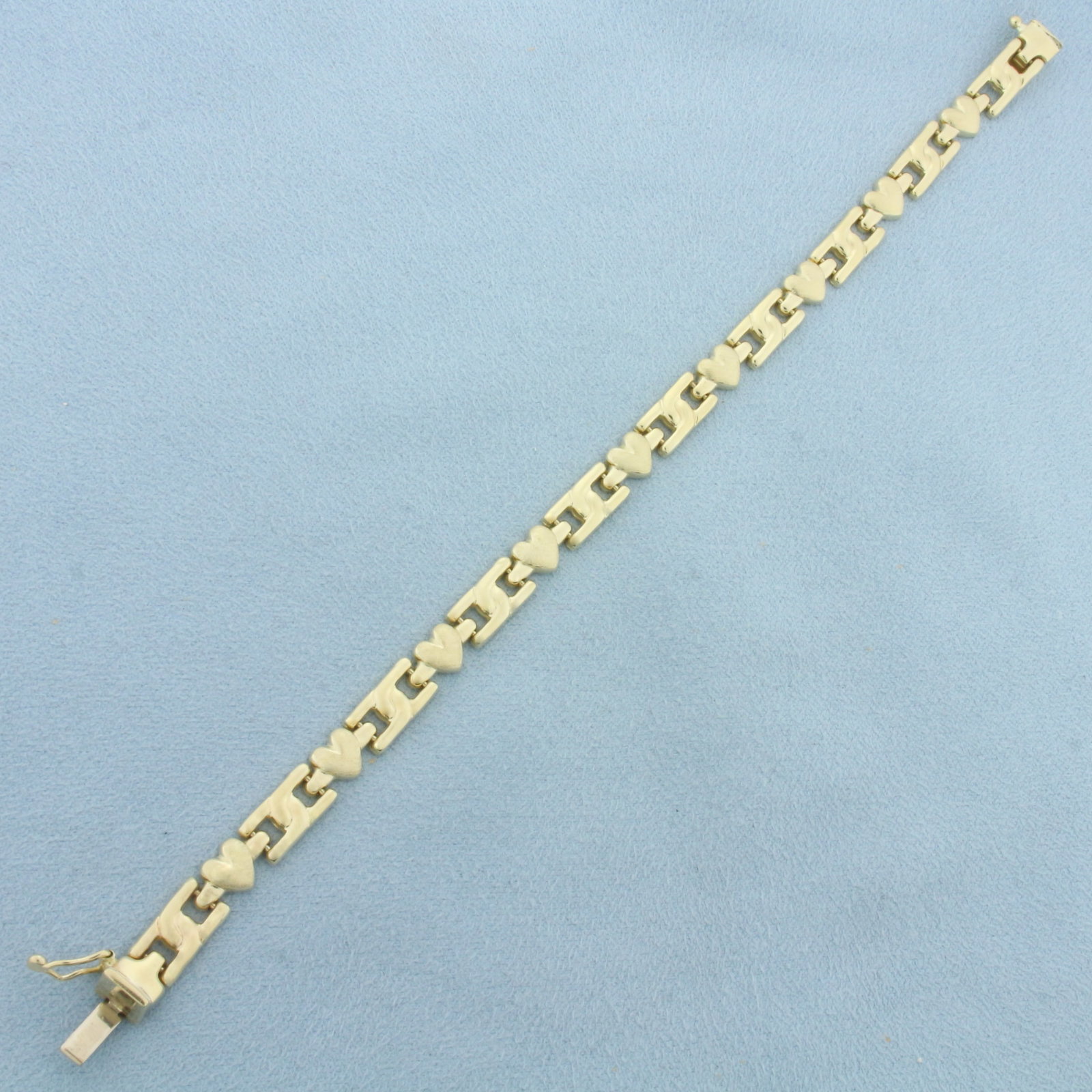 Heart Link Bracelet in 14k Yellow Gold: In 14k Yellow Gold. 7 1/4 inches long. 6mm wide. Concealed slide clasp with safety latch. 9.2g.