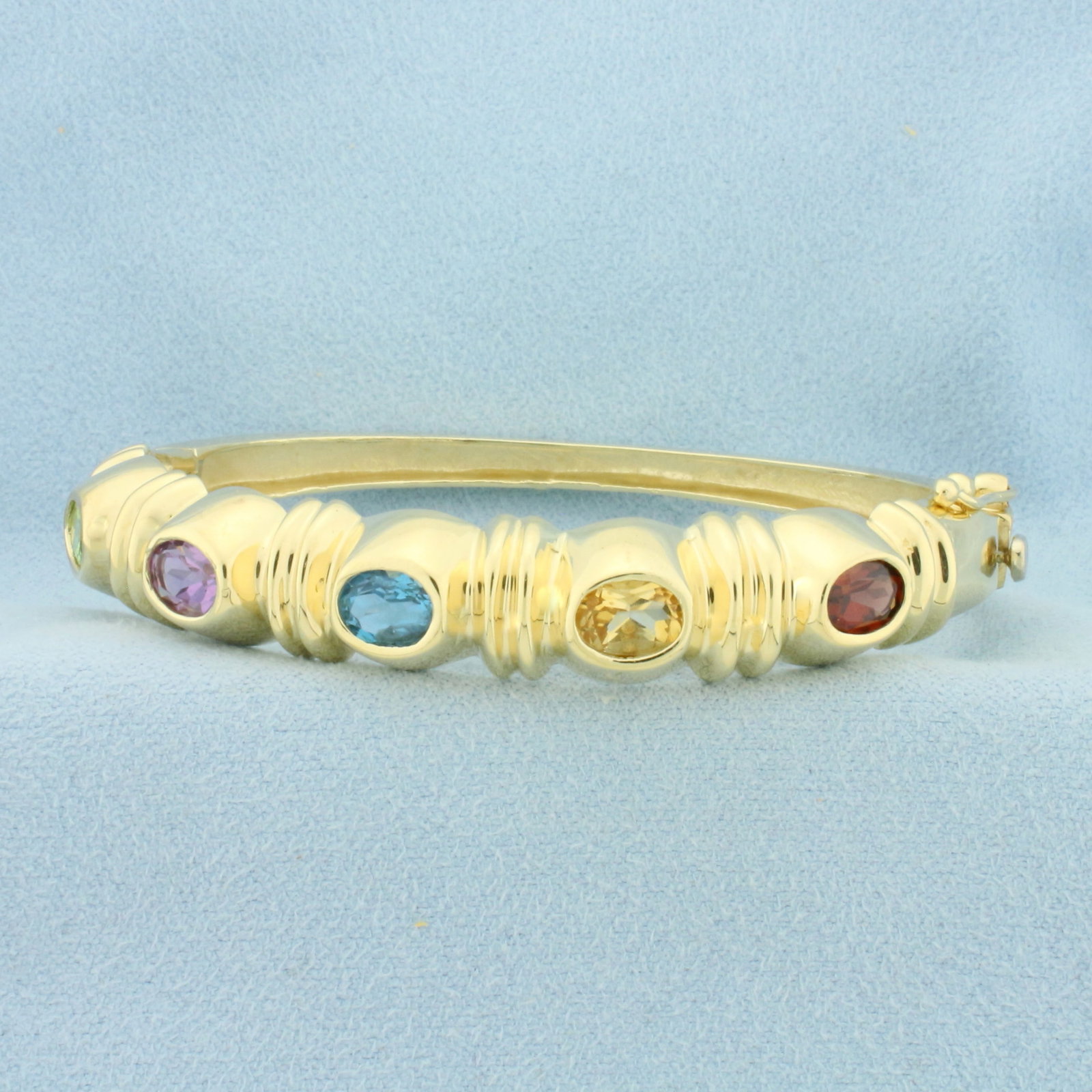 Rainbow Gemstone Bangle Bracelet in 14k Yellow Gold: In 14k Yellow Gold. Contains five 5x7mm high quality natural gemstones including: Peridot, Amethyst, Blue Topaz, Citrine, and Garnet. Interior dimensions: 2 1/4 inch by 2 inch. 10mm wide. Hinged