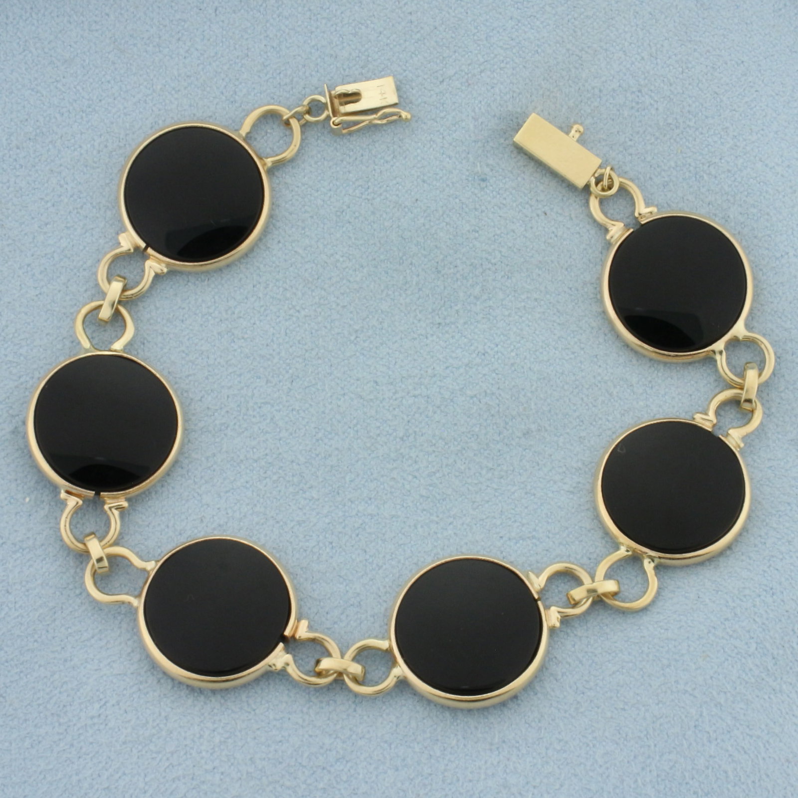 Onyx Disc Bracelet in 14k Yellow Gold: In 14k Yellow Gold. Contains six high quality 14mm onyx gemstones. 7 inches long. 15mm wide. Slide clasp with safety latch. 12.2g.