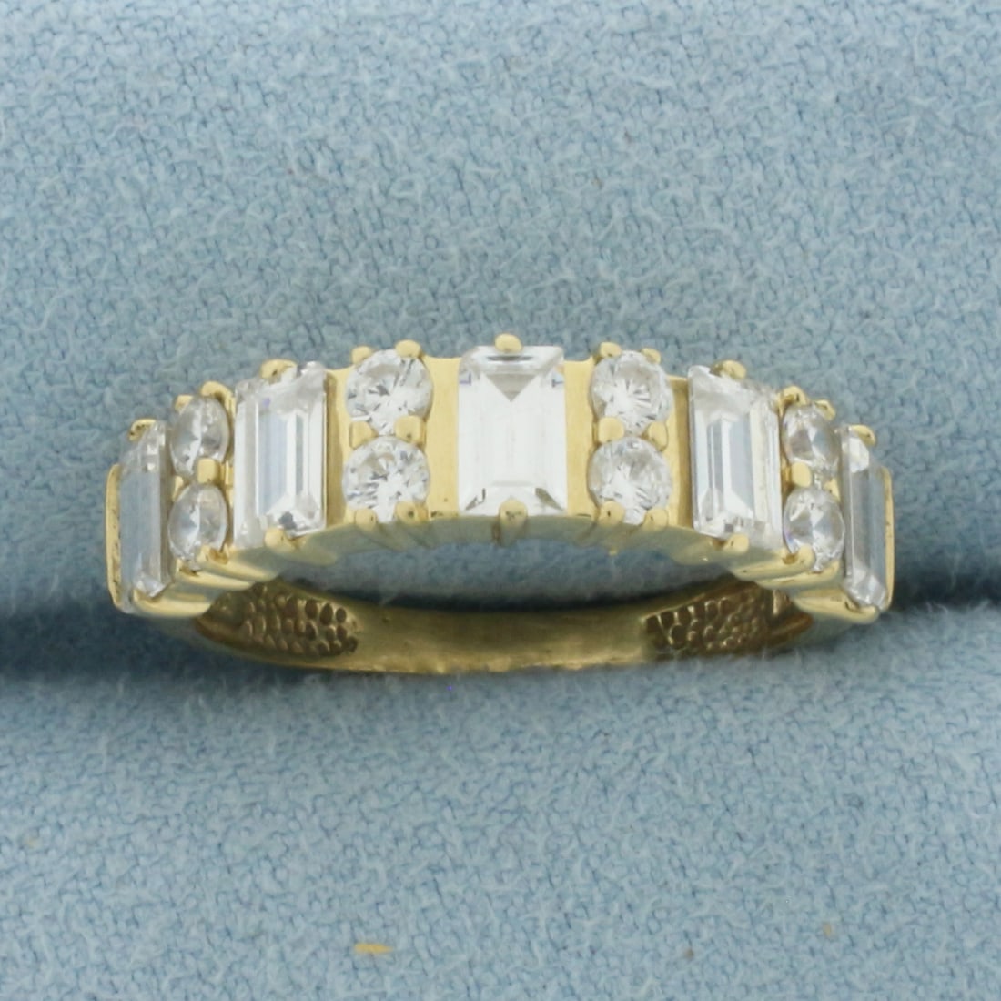 Round and Emerald Cut CZ Band Ring in 14k Yellow Gold: In 14k Yellow Gold. Contains eight 2.5mm round and five 5x3mm high quality emerald cut Cubic Zirconia gemstones with excellent cut and clarity for added brilliance. 5.8mm wide. Size 7. 2.9g.