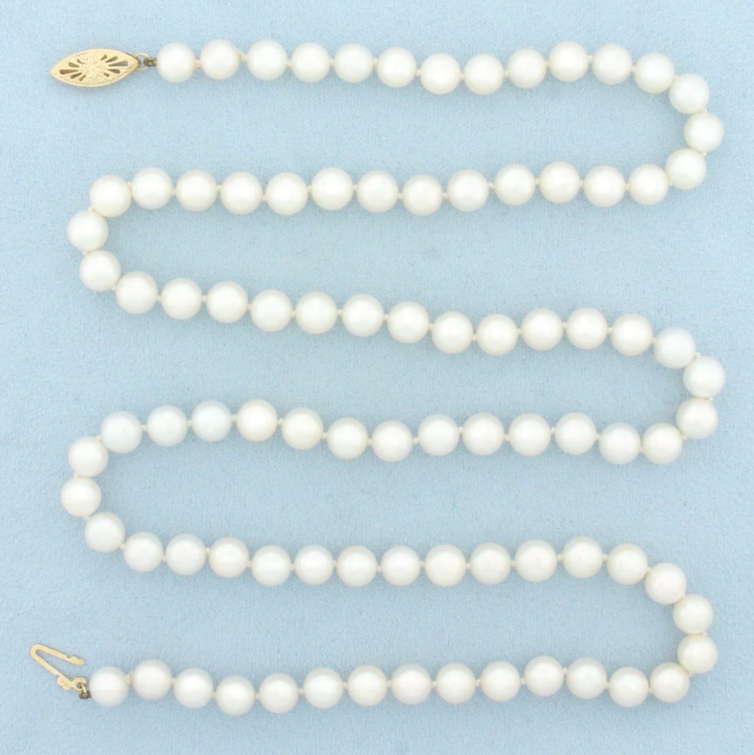 27 Inch Cultured Akoya Pearl Necklace in 14k Yellow Gold: In 14k Yellow Gold. Contains 6.6-6.8mm high quality Cultured Akoya Pearl gemstones with mirror like luster and slight pink undertone. 27 inches long. Hand knotted. Filigree locking clasp. 40.1g