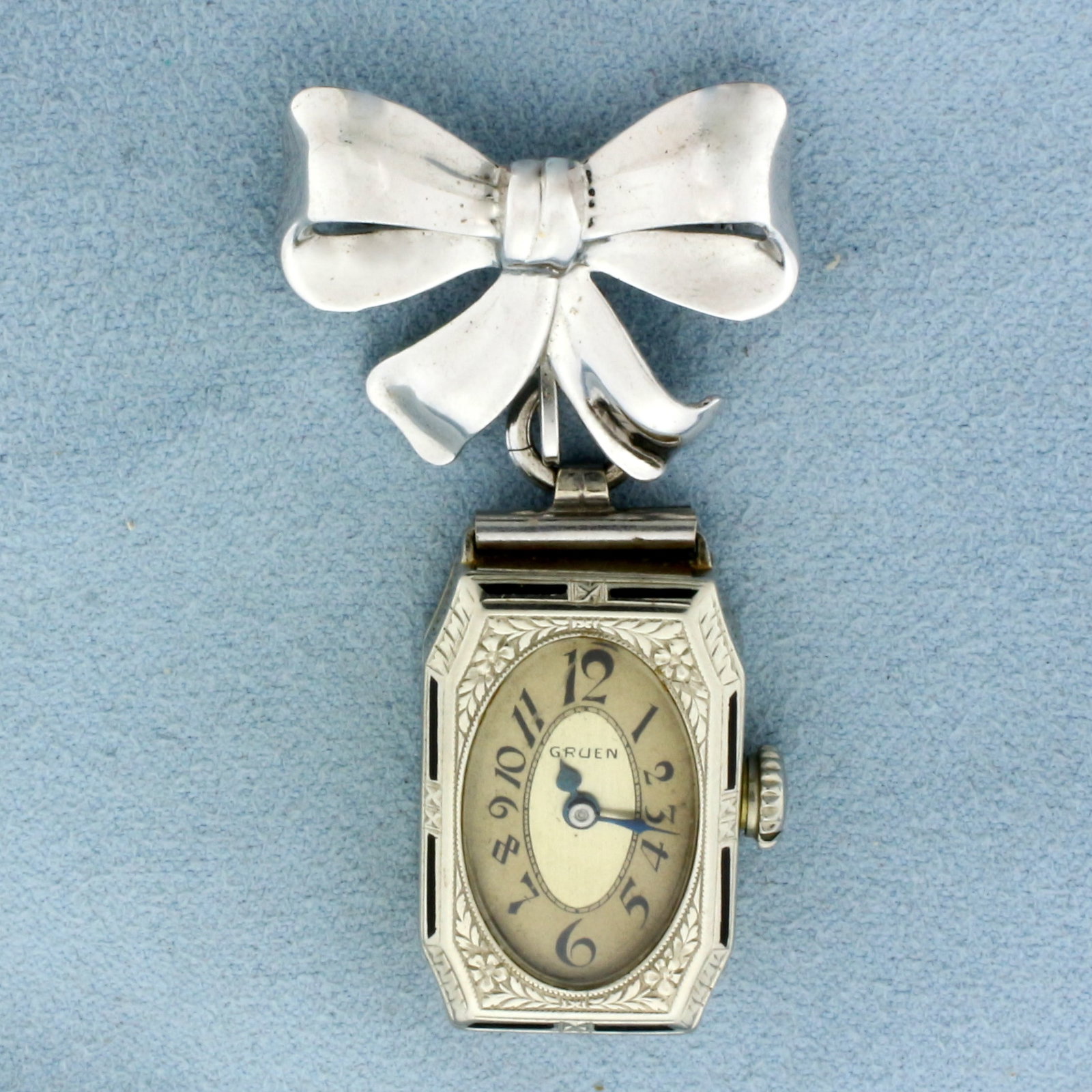 Vintage Swiss Gruen Watch Pin in 14k White Gold Case: in 14k White Gold Case with Gold filled bow pin attachment. Cincinnati 153/57. #1155708. 15 jewel windup movement runs great. Four 4 Adj. 1575941. 2 1/4 inches long. 1 inch wide. 16.4g.