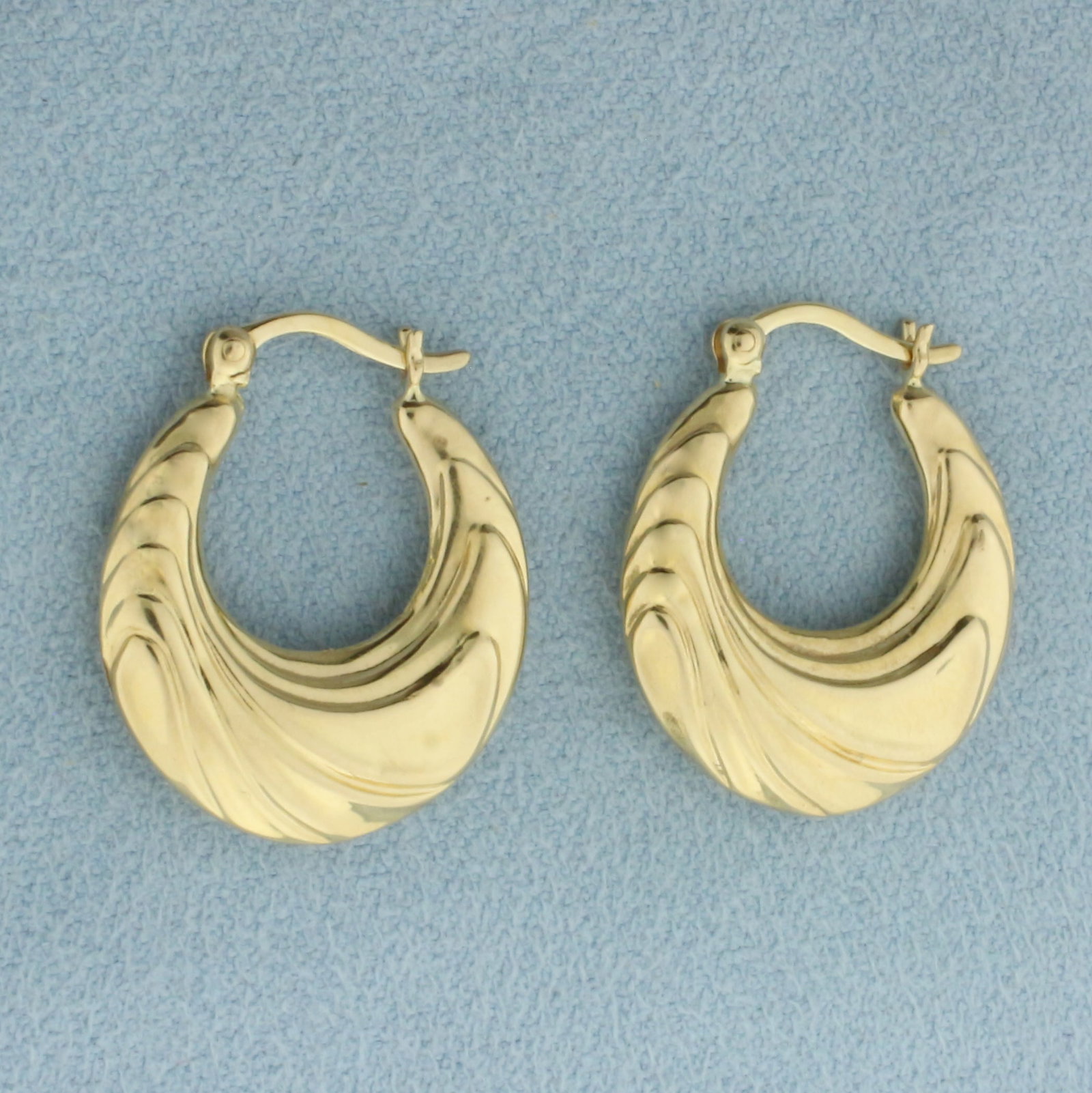 Abstract Wave Design Hoop Earrings in 14k Yellow Gold: In 14k Yellow Gold. 7/8 inch long. 4mm thick. Hinged closure. 1.6g.