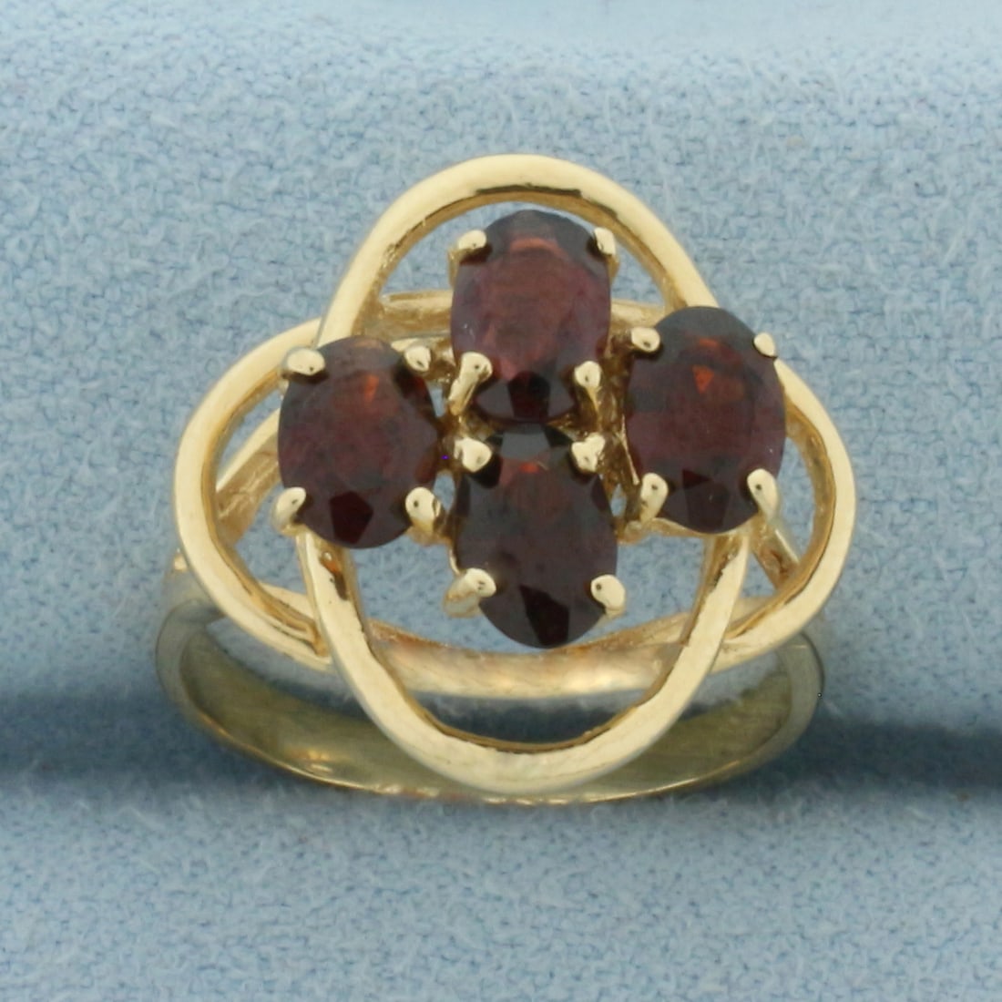 Halo Garnet Ring in 14k Yellow Gold: In 14k Yellow Gold. Contains four high quality natural 6mmx4mm oval Garnet gemstones with intense color and excellent clarity. Size 5.5. 3.7g.