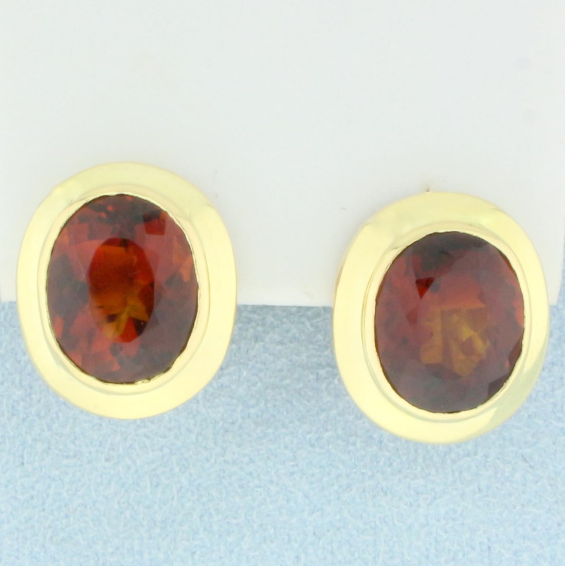 Bezel Set Citrine Stud Earrings in 18K Yellow Gold: In 18K Yellow Gold. Each earring contains one high quality natural 12.5x10.5mm oval cut AAA Citrine gemstone with very desirable honey orange amber color and excellent clarity. 3/4 inches long. 5/8 in