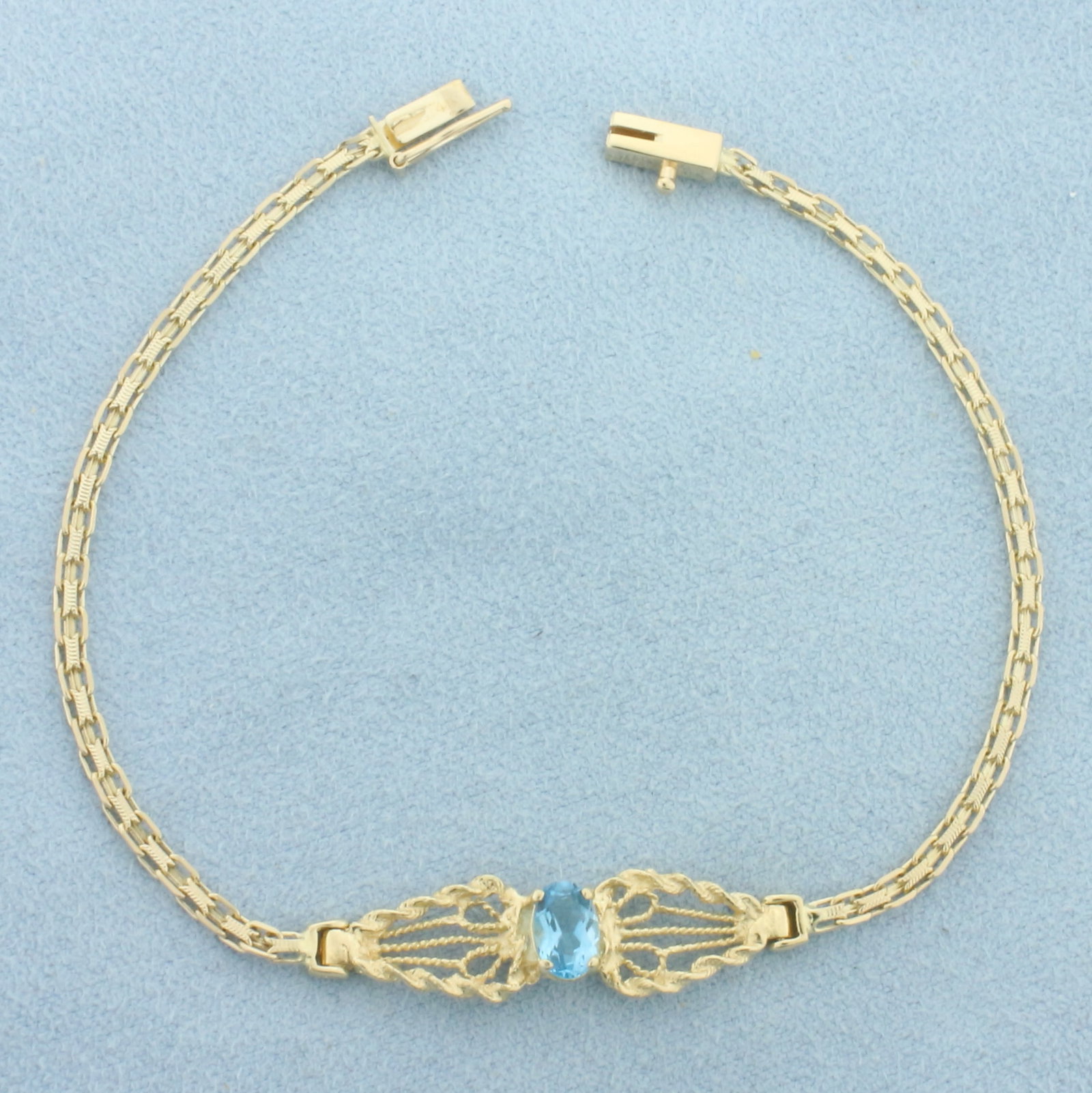 Swiss Blue Topaz Bracelet in 14k Yellow Gold: In 14k Yellow Gold. Contains one 6x4mm high quality natural Swiss Blue Topaz gemstone with electric blue color and excellent clarity. 7 inches long. 8mm wide at center. Slide clasp with safety latch. 