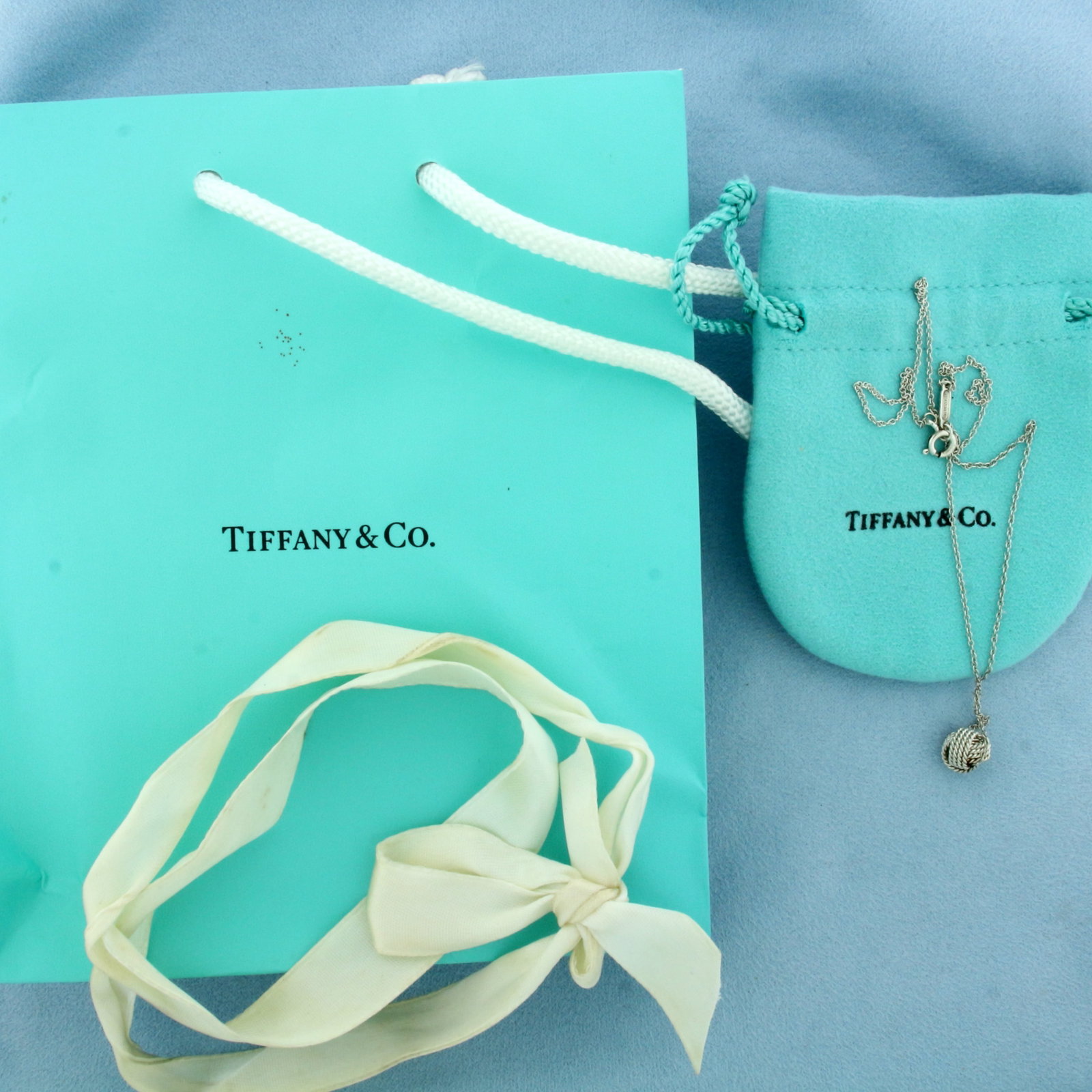 Tiffany and Co. Love Knot Necklace in Sterling Silver: In .925 Sterling Silver. Guaranteed authentic. 16 inches long. 1/4 inch long knot. Includes original pouch, bag, and ribbon.