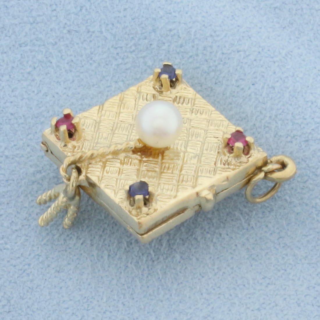 Graduation Cap Locket in 14k Yellow Gold: In 14k yellow gold. Contains one high quality 4.7mm cultured pearl with high luster. Also contains two Sapphire and one Ruby 2mm high quality gemstones with vibrant color and excellent clarity. 1 inch
