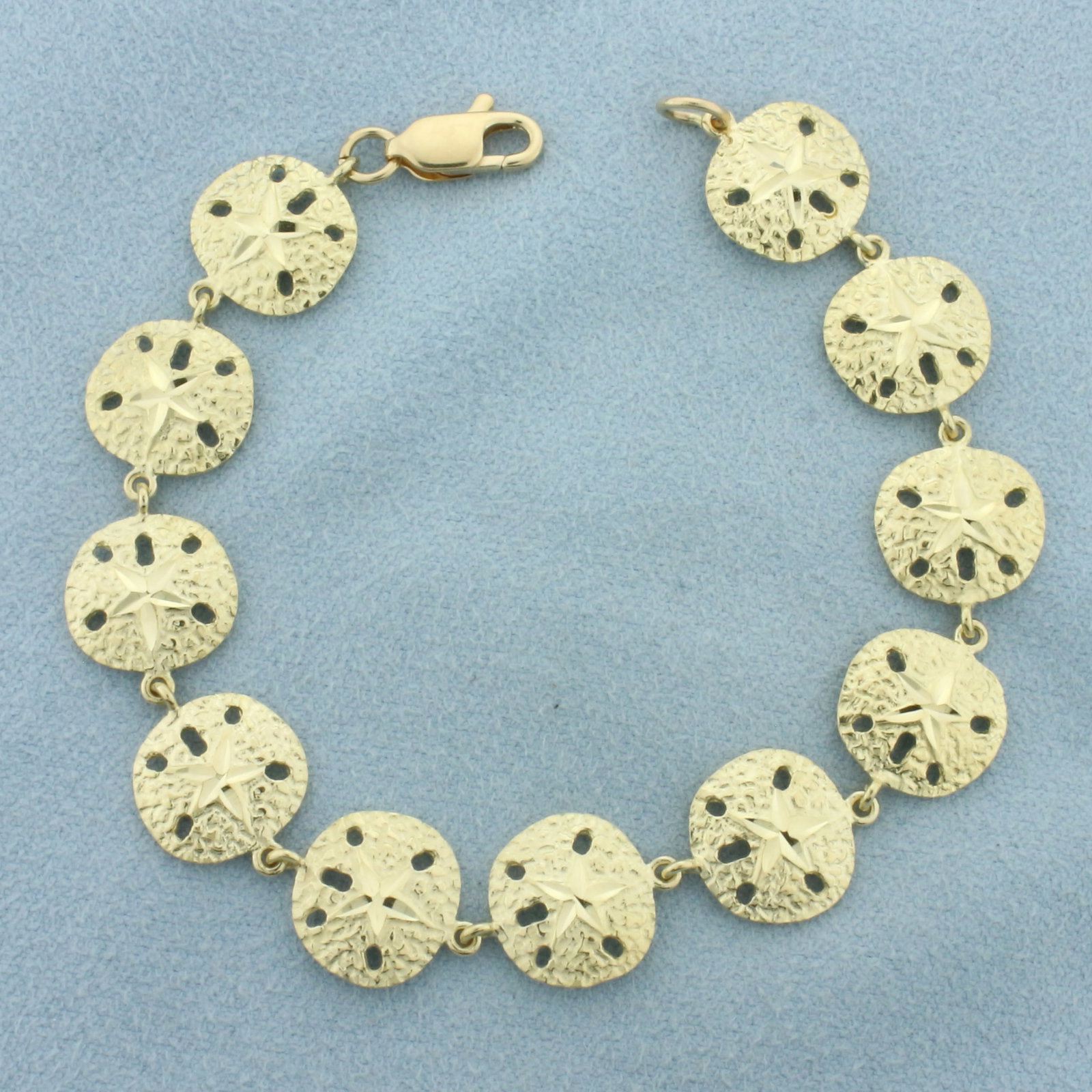 Diamond Cut Sand Dollar Bracelet in 14k Yellow Gold: In 14k Yellow Gold. 6 7/8 inch long. 12mm wide. Lobster clasp. 9.1g.