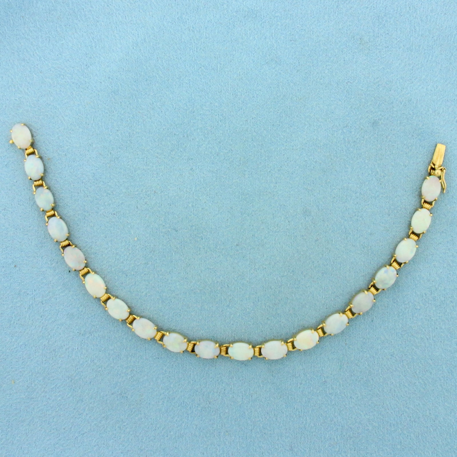 Opal Tennis Bracelet in 14k Yellow Gold: In 14k Yellow Gold. Contains nineteen 5x7mm high quality natural Opal gemstones, with excellent play of color, with flashes of red, orange, green, and blue. 7 inches long. 5mm wide. Concealed slide cl