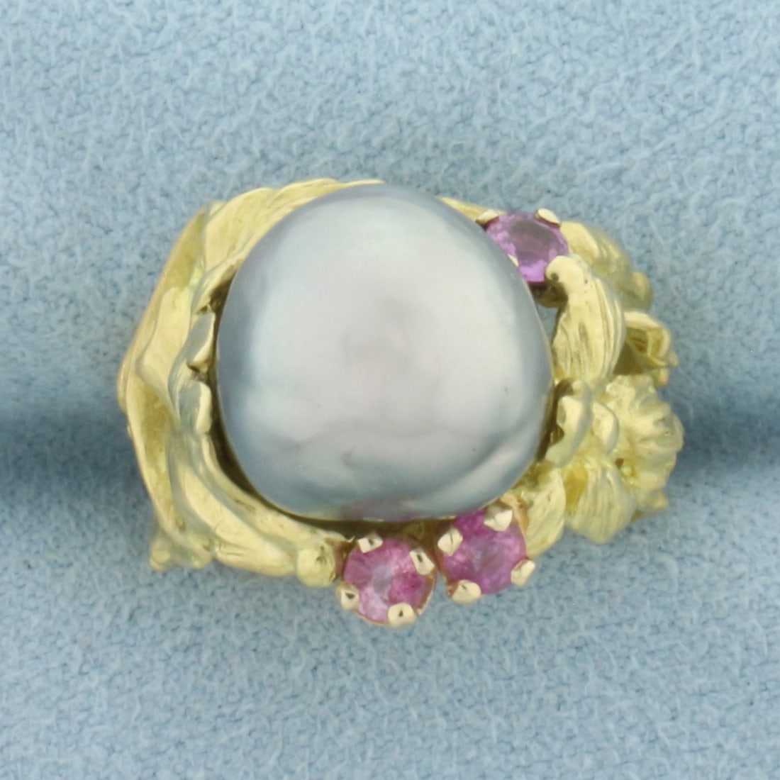 Designer Angela Conty Tahitian Pearl and Pink Sapphire Flower Ring in 18k Yellow Gold: In 18k Yellow Gold. Contains one high quality 12mm baroque Tahitian pearl with high luster and beautiful peacock color. Also contains three 3mm high quality natural Pink Sapphire gemstones with bright