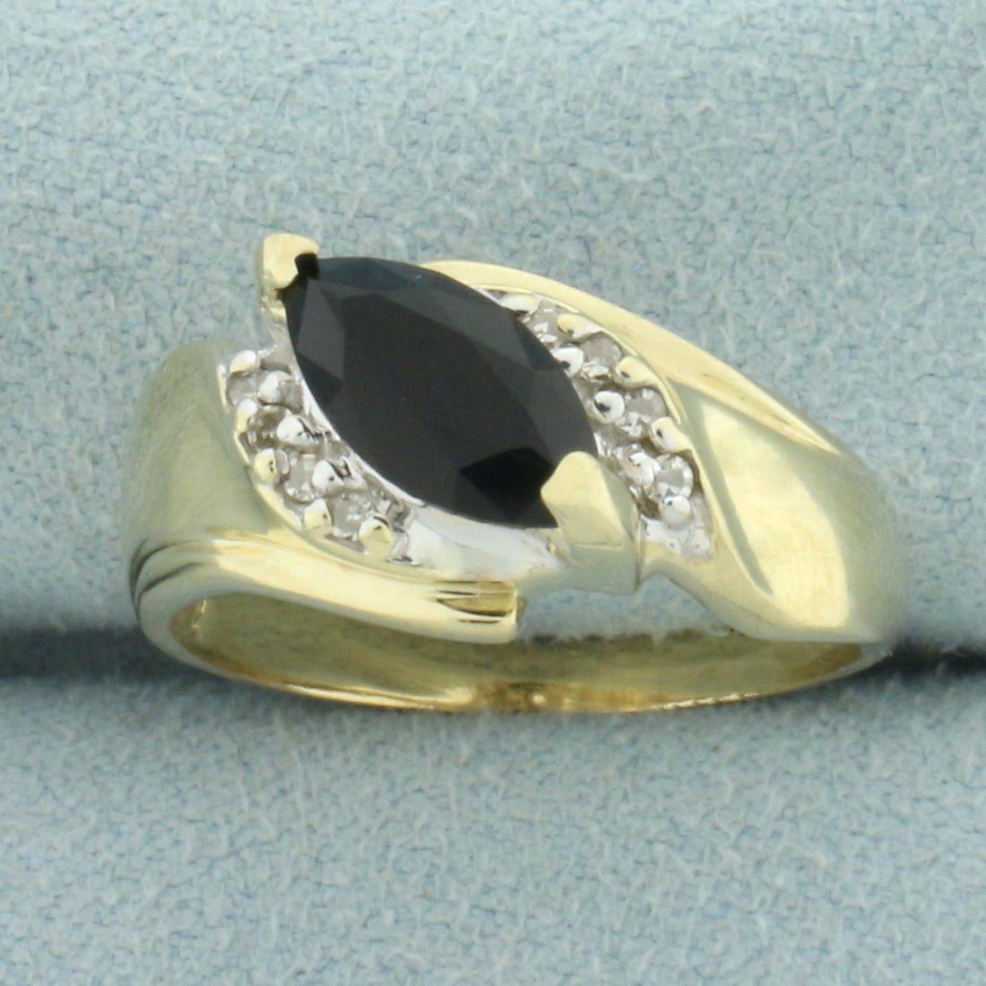 Diagonal Sapphire and Diamond Ring in 10k Yellow Gold: In 10k yellow gold. Contains one high quality natural 10mm marquise Sapphire gemstone with deep midnight blue color. Also contains eight high quality .01ct diamonds, SI clarity/H color. 10mm wide at c