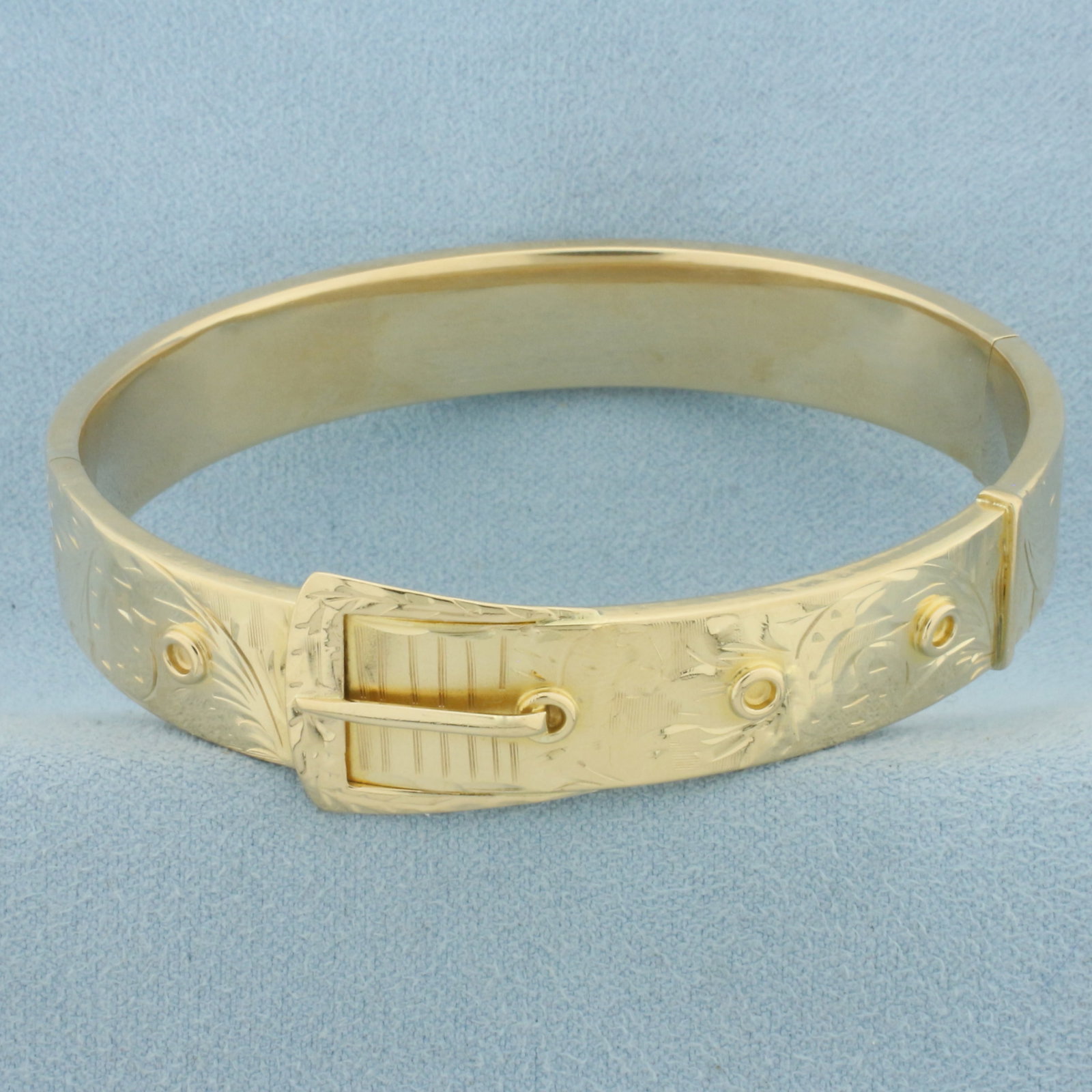 Belt Design Bangle Bracelet in 14k Yellow Gold: In 14k Yellow Gold. Interior dimensions: 2 1/2 inch by 2 1/4 inch. 16.7mm wide at widest. Hinged closure. 20.7g.