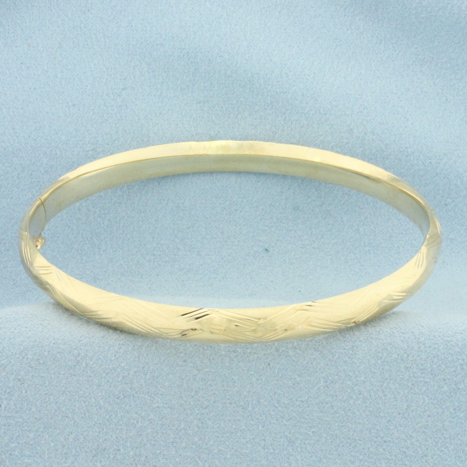 Etched Wave Design Hinged Bangle Bracelet in 14k Yellow Gold: In 14k Yellow Gold. Interior dimensions: 2 1/2 by 2 1/4 inches. 6mm wide. Bar slide hinged closure. 6.2g.