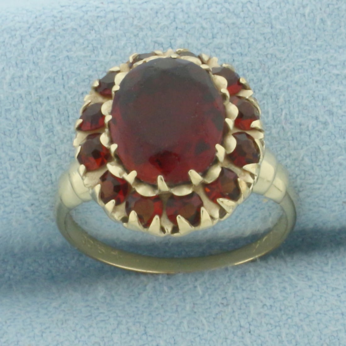 Vintage Garnet Halo Ring in 10k Yellow Gold: In 10k Yellow Gold. Contains one 10x8mm high quality oval cut natural Garnet gemstone, approximately 3ct, with vibrant color and excellent clarity. Minor abrasion on stone, indicative of age. Also con