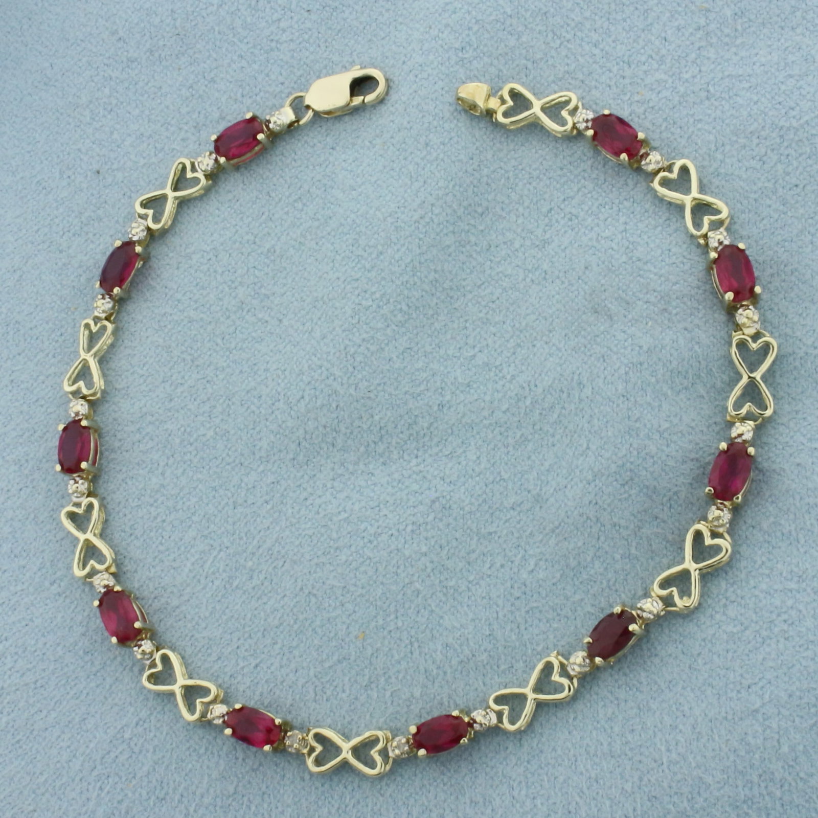 Ruby and Diamond Heart Link Bracelet in 10k Yellow Gold: In 10K Yellow Gold. 7 1/4 inches long. 4.1mm wide. Contains 10 high quality natural 5mm Ruby gemstones, approximately 2.5ct total weight, with bright color and excellent clarity. Also contains 2 high 