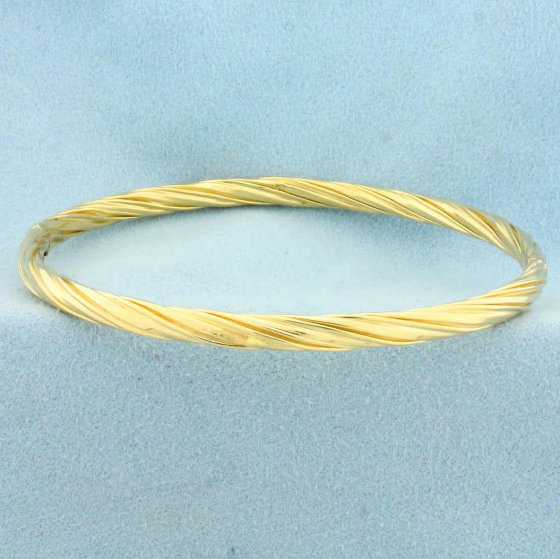 Hinged Twisting Design Bangle Bracelet in 14k Yellow Gold: In 14k Yellow Gold. Interior dimensions: 2.5 inch by 2.25 inch. 4.3mm wide. Hinged closure. 7.3g.